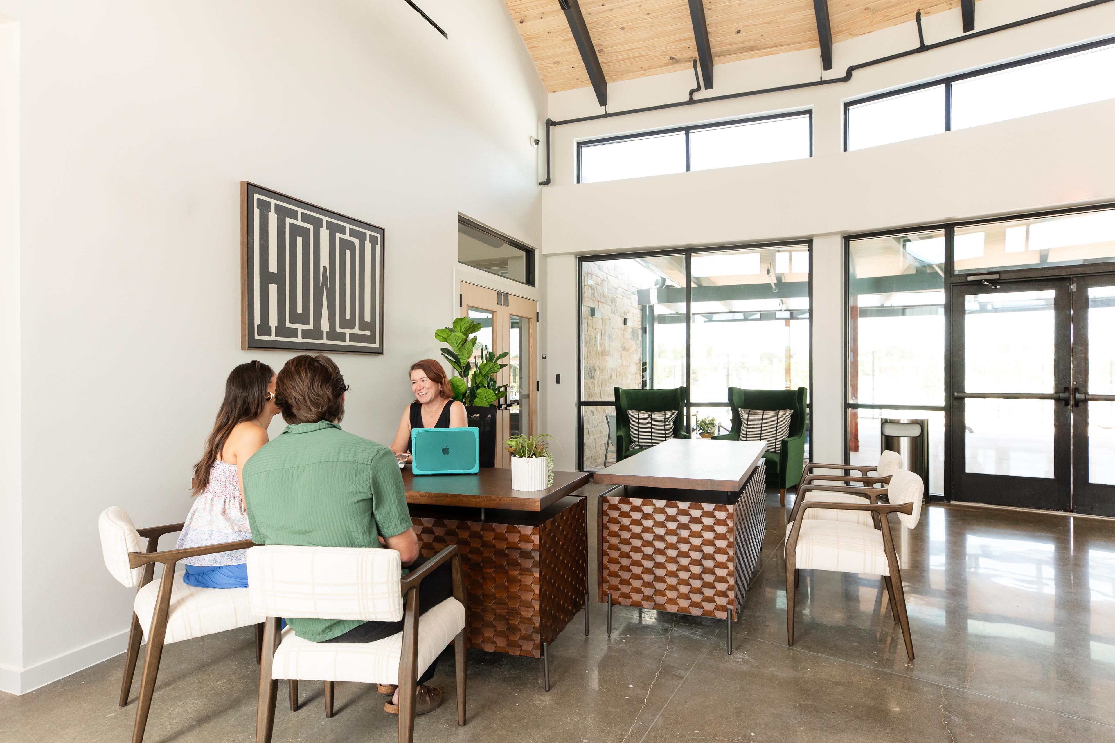 Welcoming reception desk at Emberly in Beasley, Texas by Davidson Homes with carved wood furniture, plants, and large windows