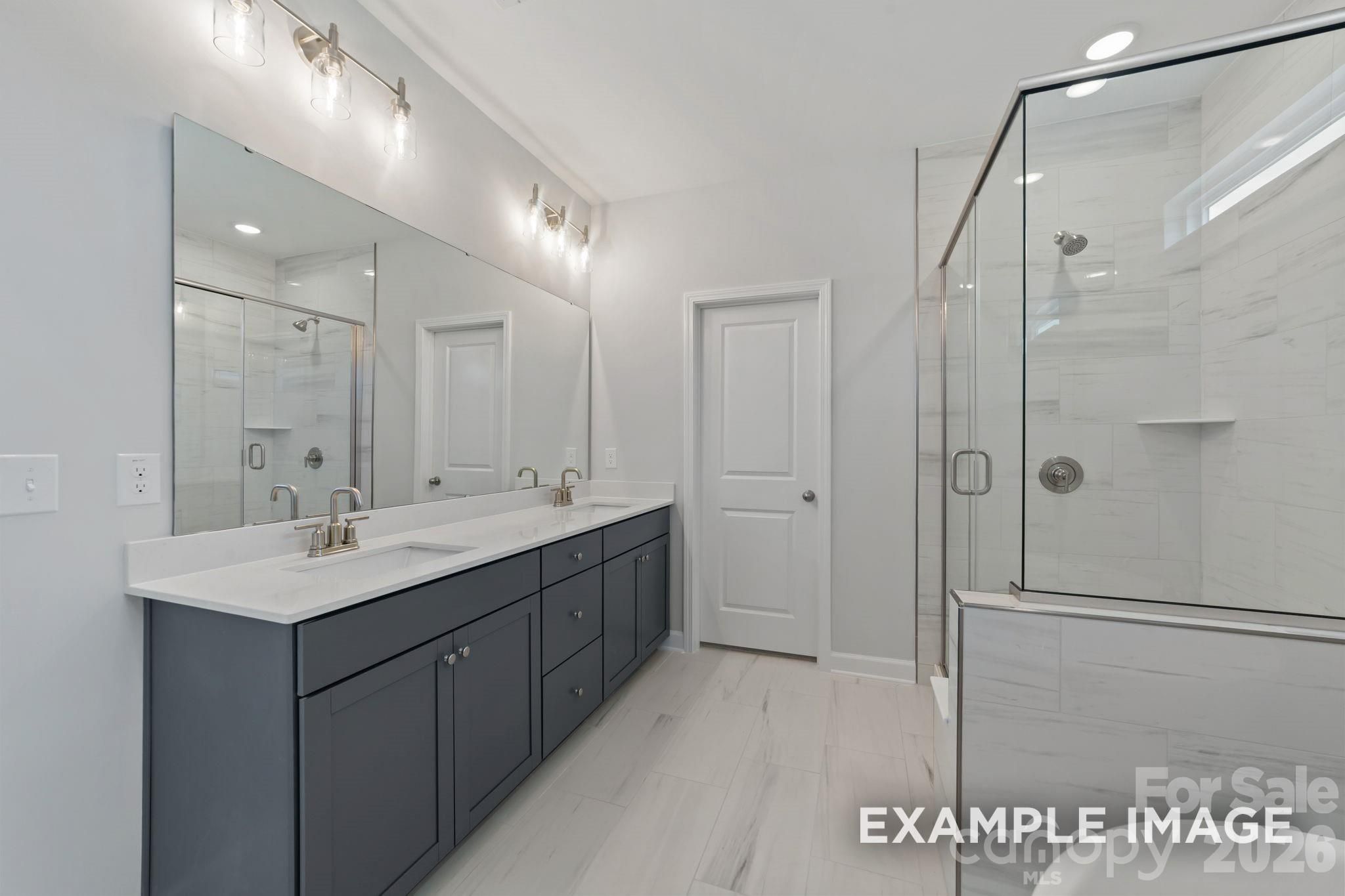 Modern master bathroom with dual vanity, quartz countertops, and glass-enclosed shower in Windgate, Mooresville home.