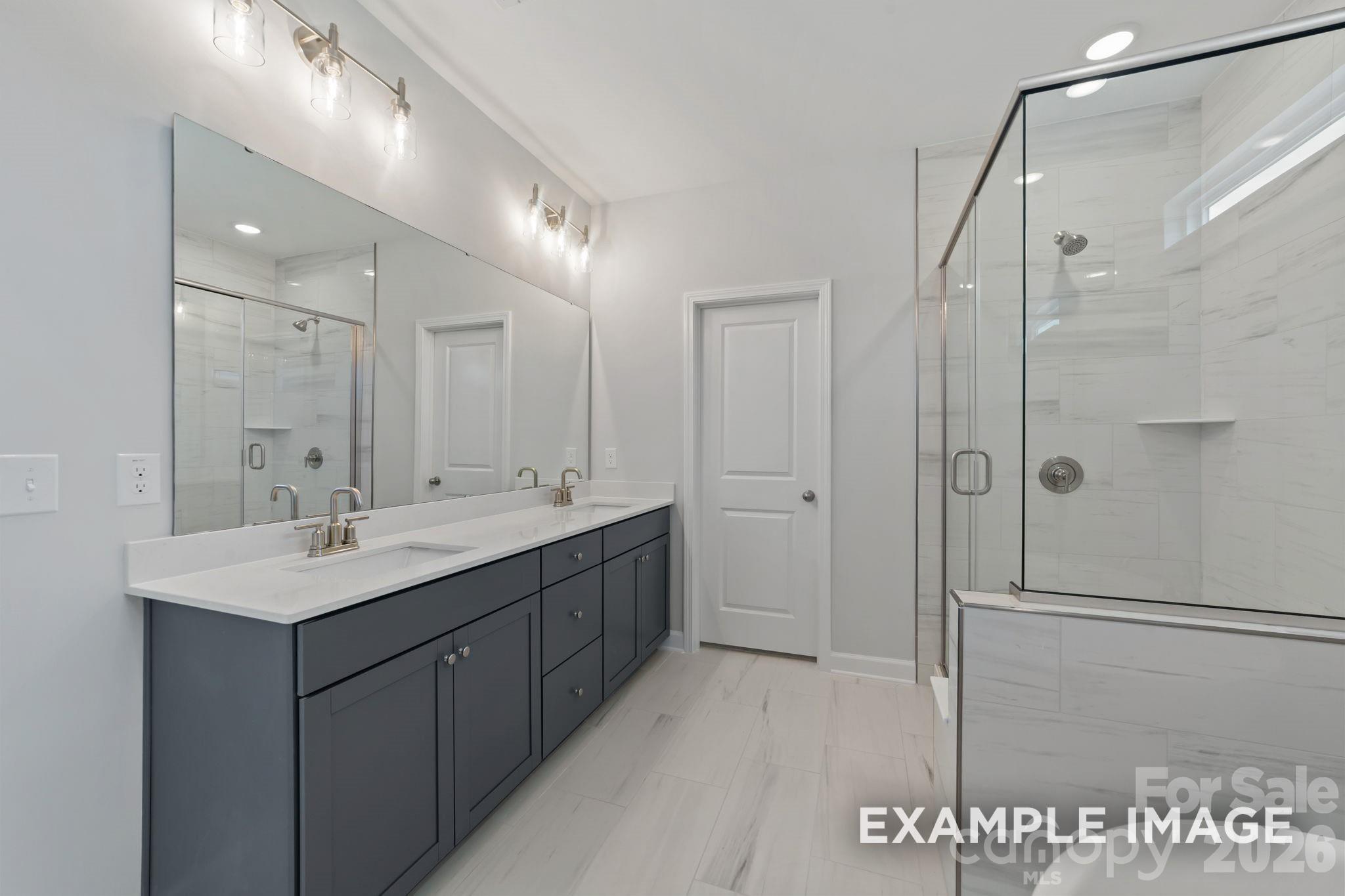 Modern master bathroom with dual vanity, quartz countertops, and glass-enclosed shower in Windgate, Mooresville home.