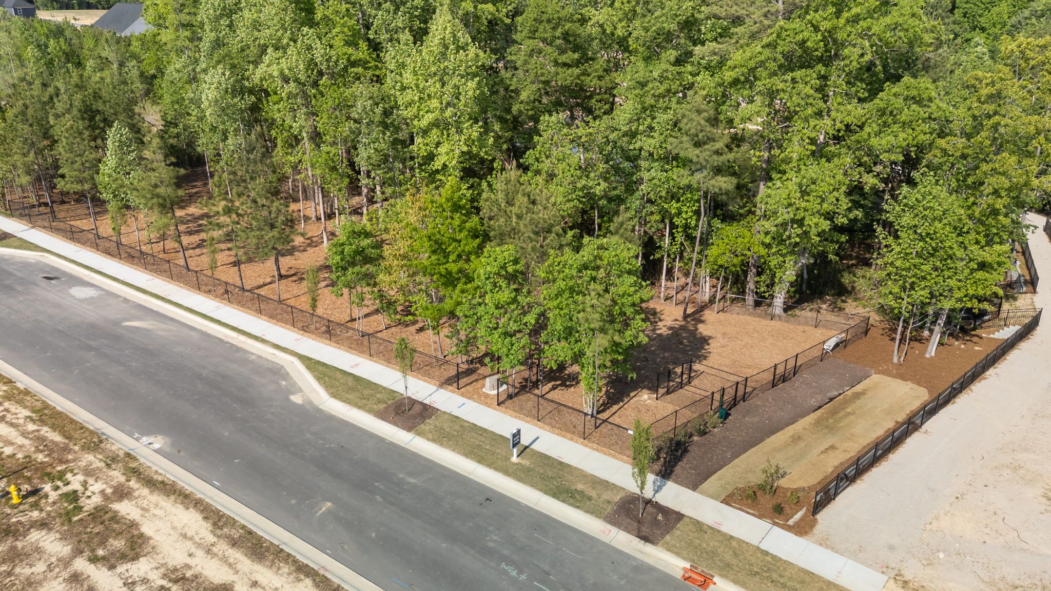 Fenced-in community dog park with mature trees at Wendell Ridge in Wendell, NC by Davidson Homes.