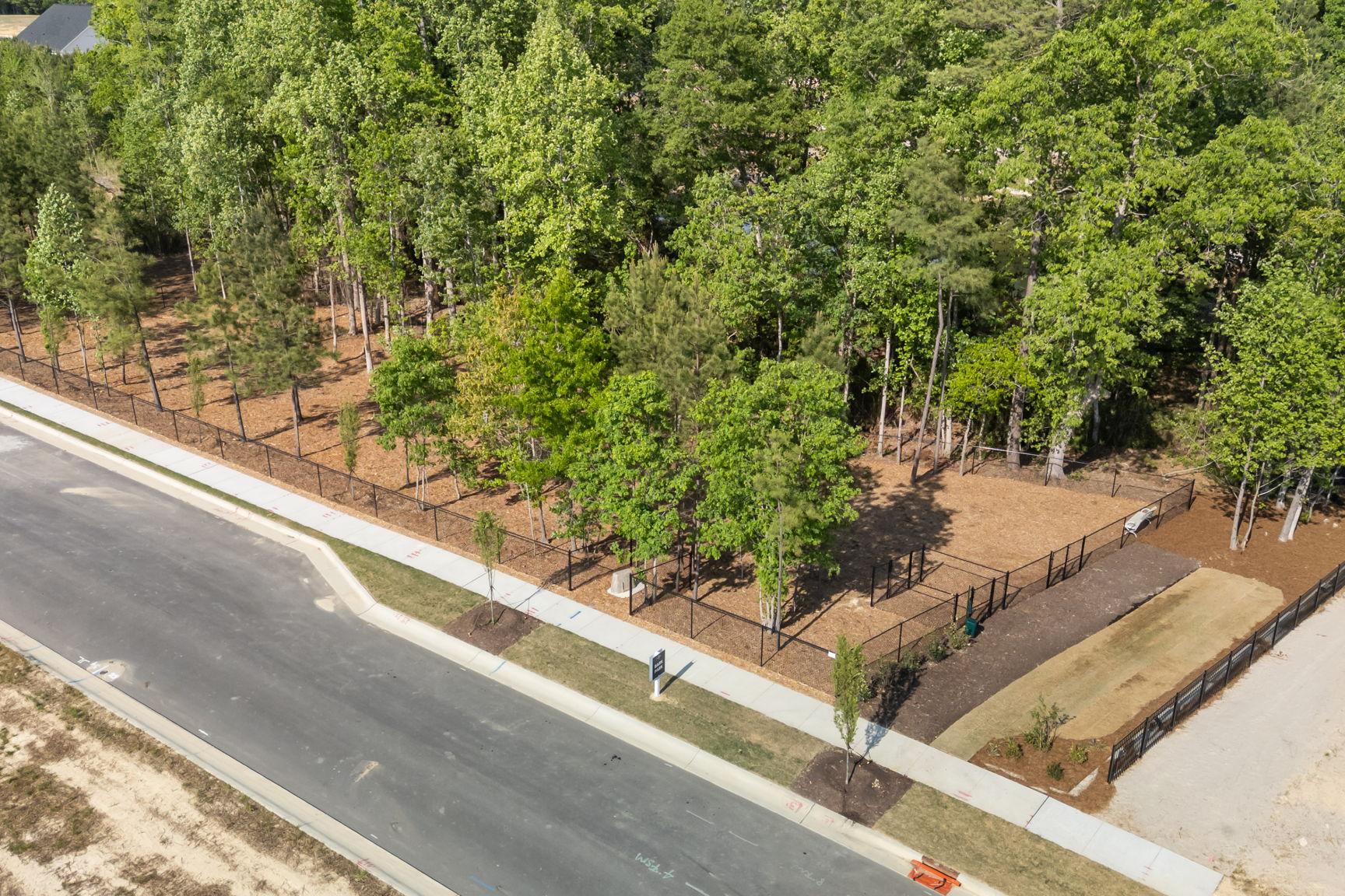 Fenced-in community dog park with mature trees at Wendell Ridge in Wendell, NC by Davidson Homes.