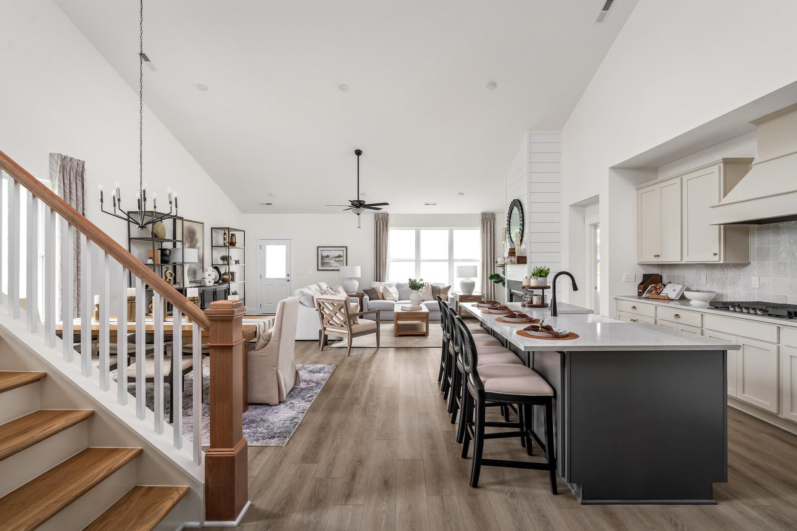 Open-concept kitchen dining living area in Woods Crossing Gallatin TN with white shiplap walls vaulted ceiling hardwood floors and modern island