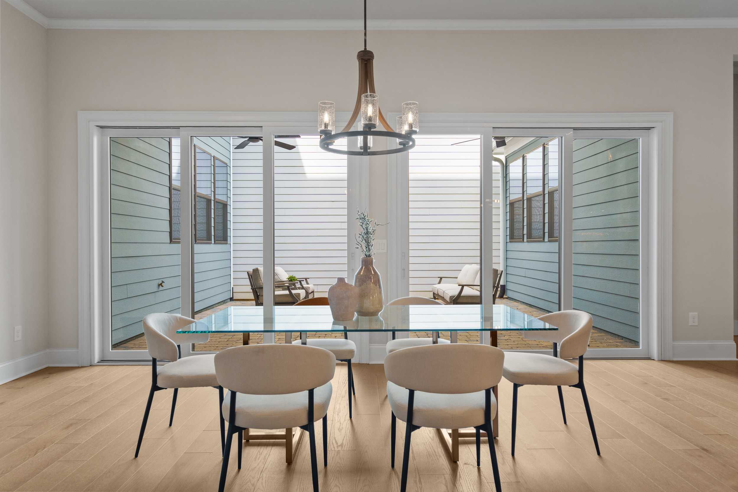 Spacious dining room at The Village at Towne Lake in Woodstock Georgia featuring glass table, chandelier, hardwood floors, and screened porch views