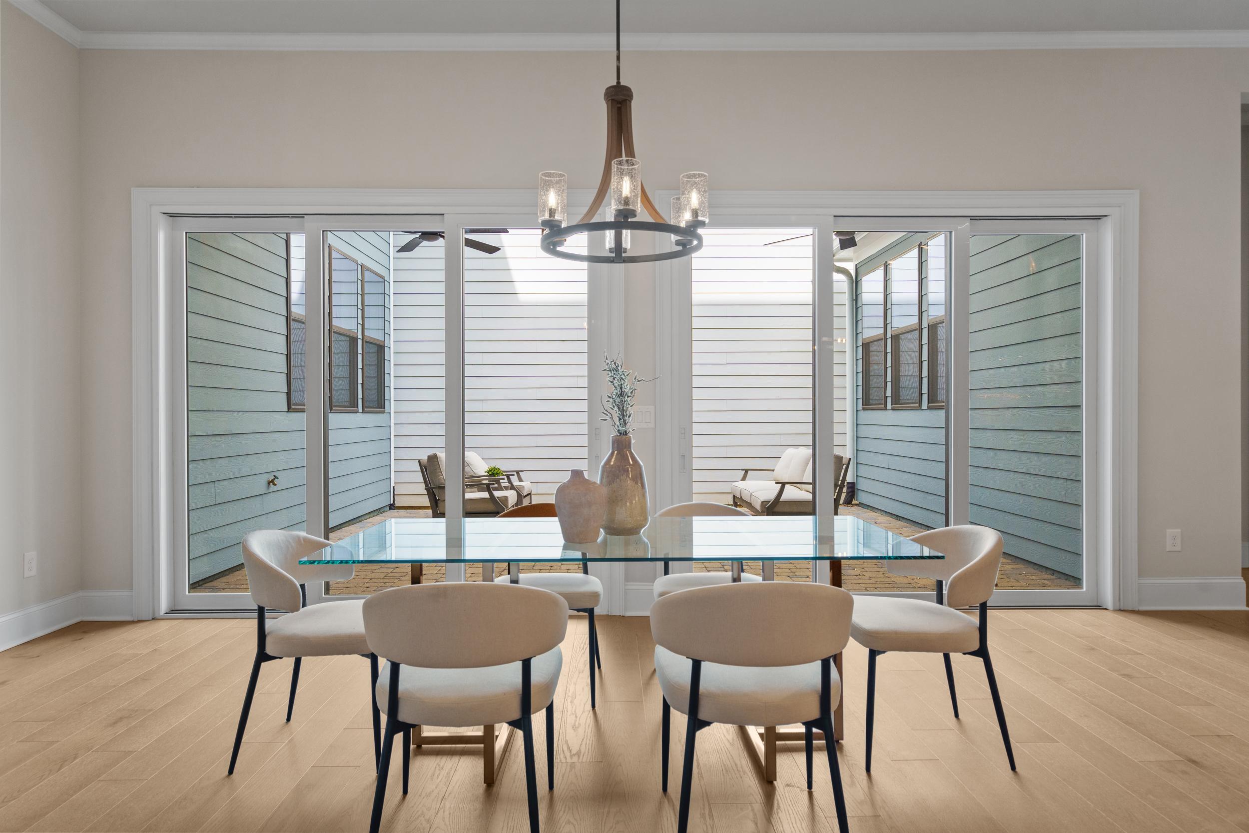 Spacious dining room at The Village at Towne Lake in Woodstock Georgia featuring glass table, chandelier, hardwood floors, and screened porch views