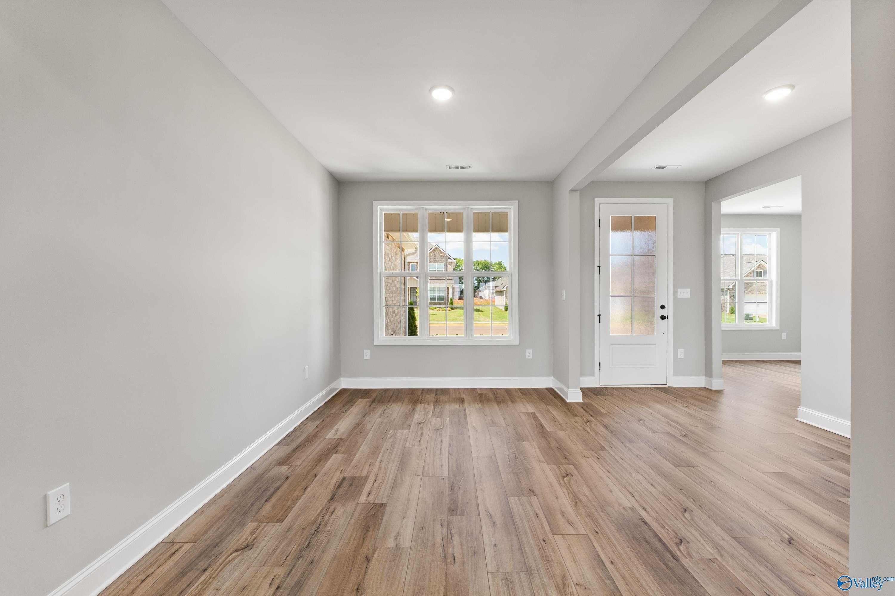 Bright family room with gray walls, hardwood floors, large windows, and French doors to backyard in The Rockford B, Toney, Alabama