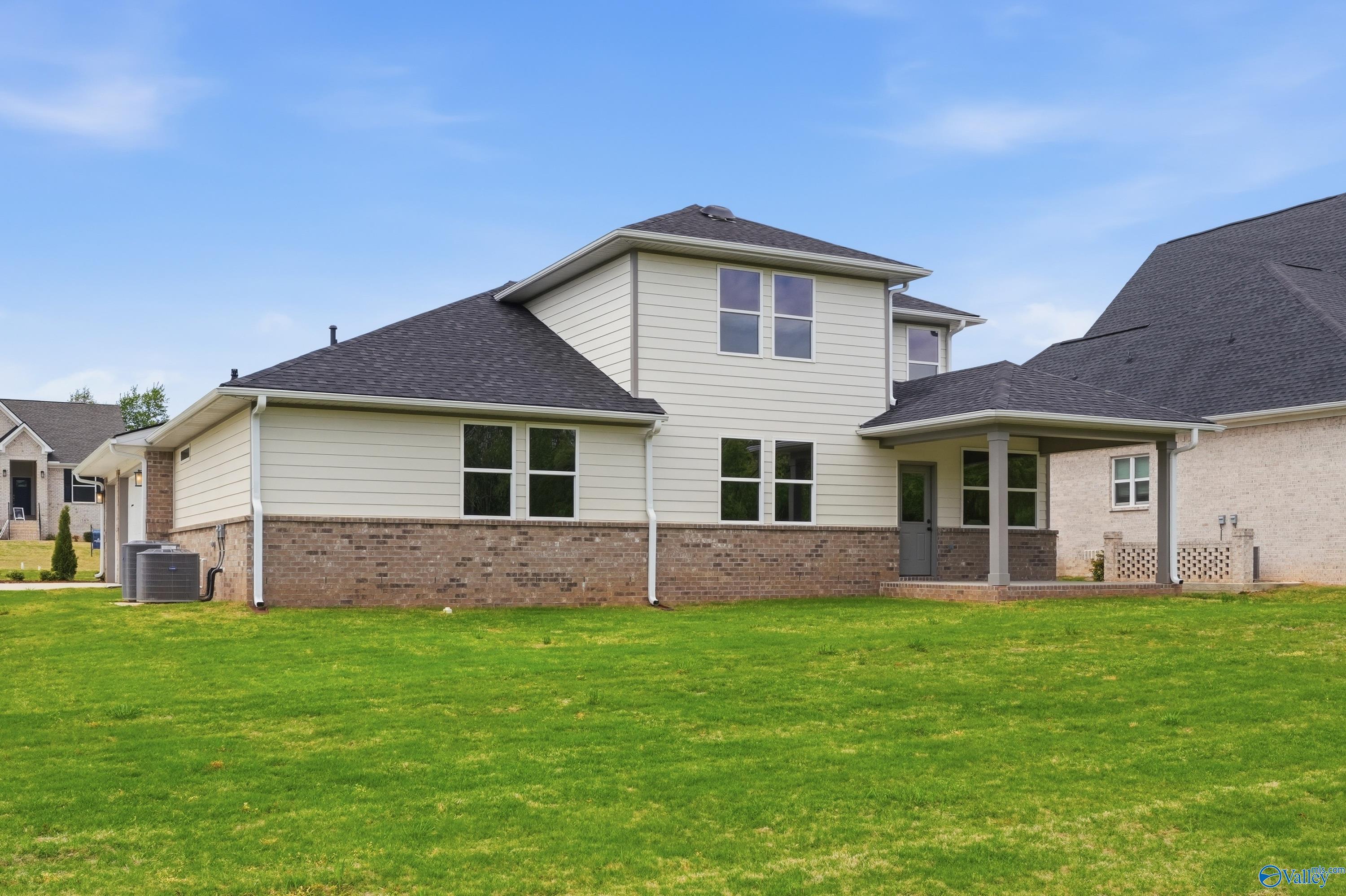 Two-story Davidson Homes Dorado with beige siding, brick accents, covered patio, and lush green lawn in Riverton Preserve, Huntsville