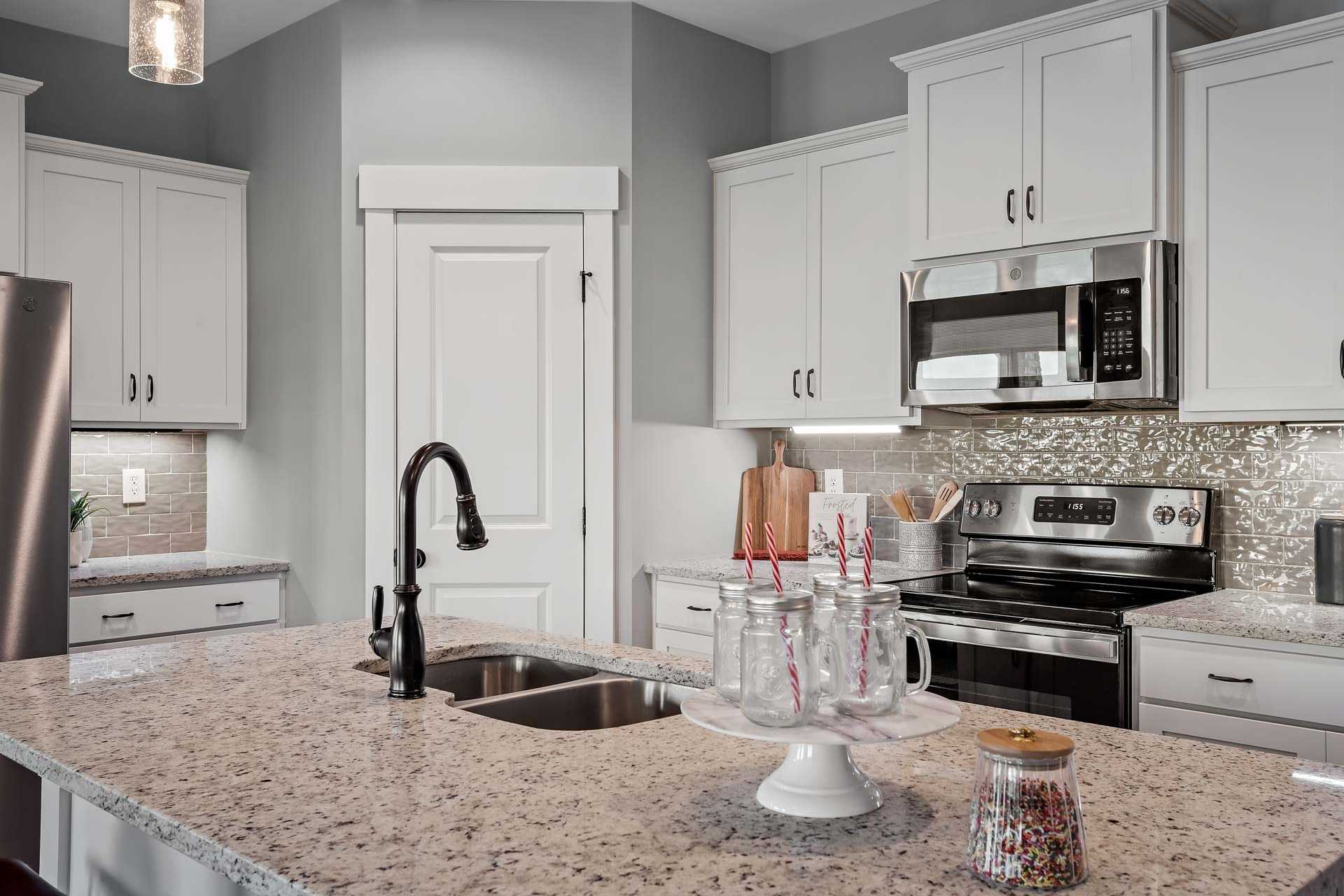 Modern kitchen in Heritage Lakes home, New Market Alabama with white shaker cabinets, granite counters, and stainless steel appliances