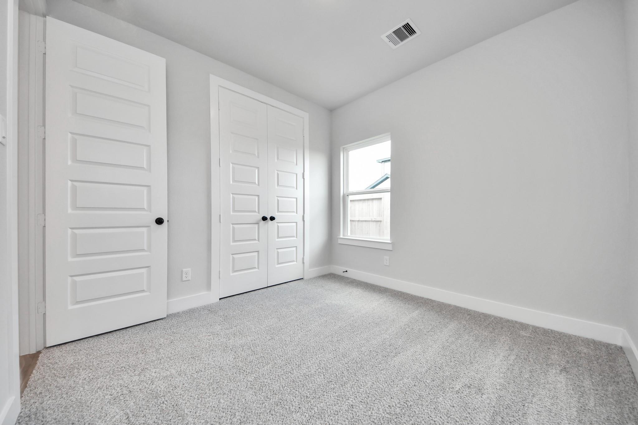 Bright secondary bedroom with plush carpet and double-door closet in The Laguna C floor plan by Davidson Homes in Katy.