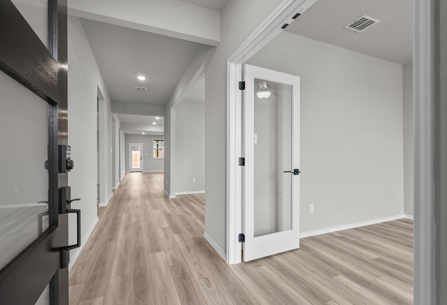 Bright foyer and home office entry with glass-paneled door and wood-style flooring in The Glenwood D single-family home.