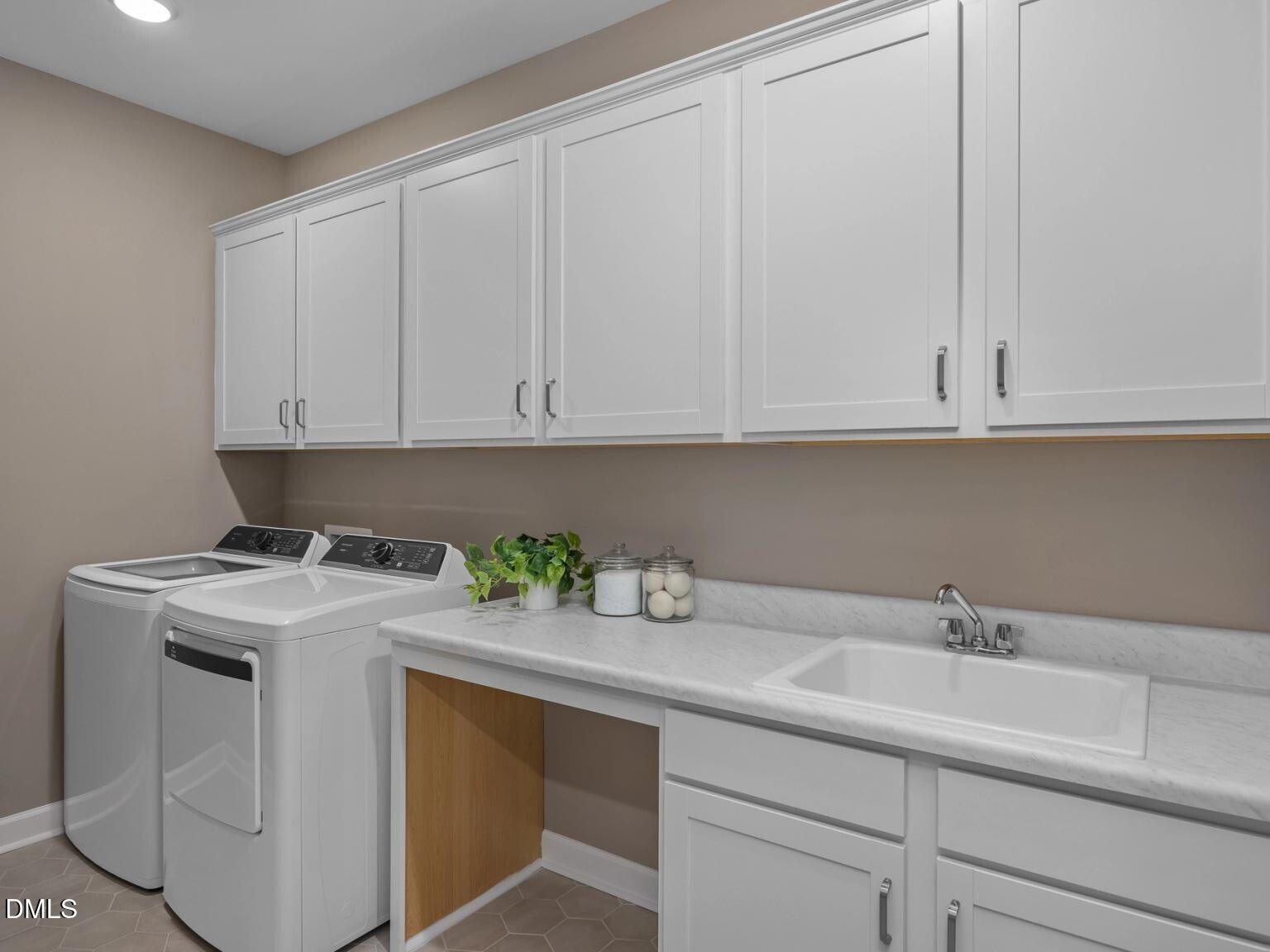 Modern laundry room featuring white washer, dryer, cabinets, utility sink in Davidson Homes The Hickory II D, Wake Forest, NC