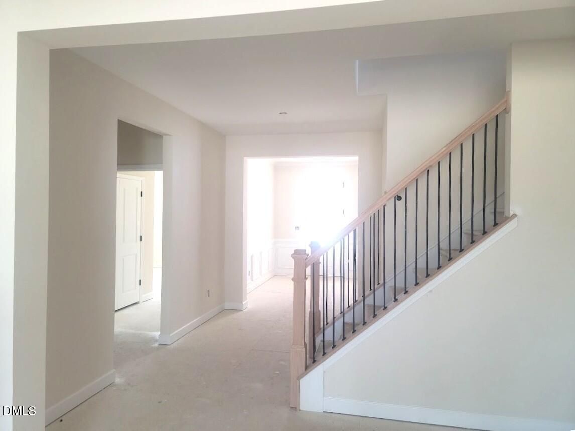 Elegant open foyer with wooden staircase and black metal railing in 4-bedroom Davidson Homes The Cypress B II, Angier, NC