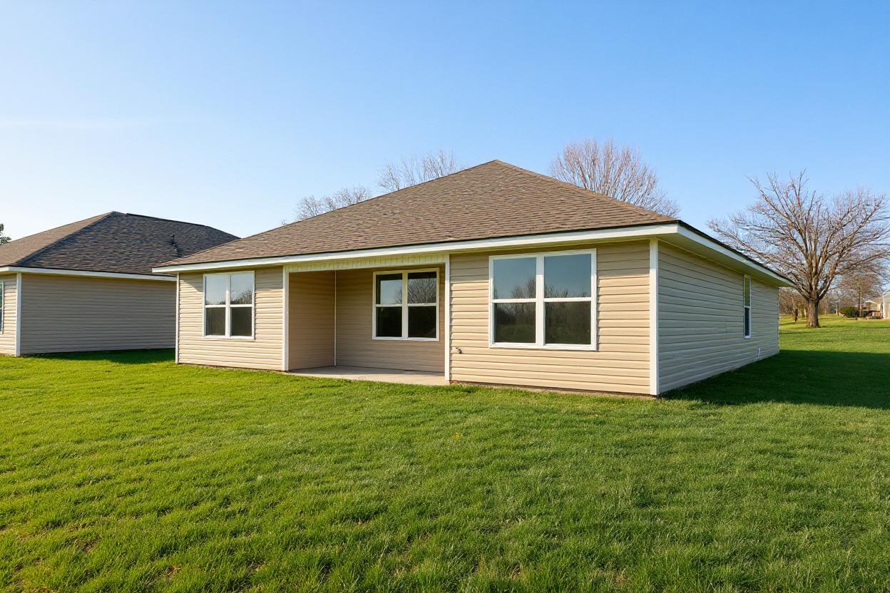 Beige single-story ranch home exterior at Chapel Hill in Athens Alabama with covered porch green lawn and blue sky