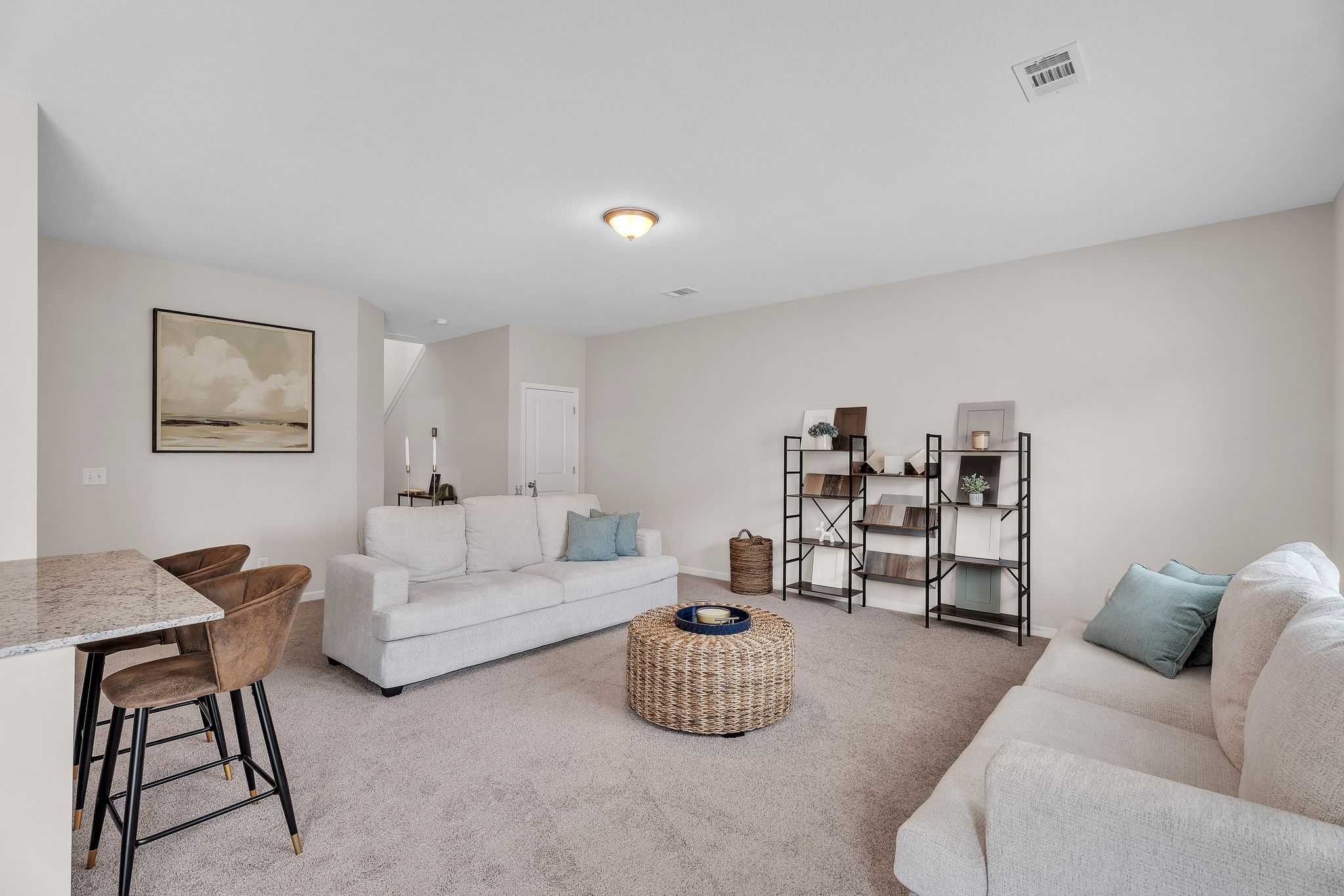 Cozy bonus room in Summer Vineyard home by Davidson Homes, Phenix City AL with white sofas, bar stools, and neutral decor