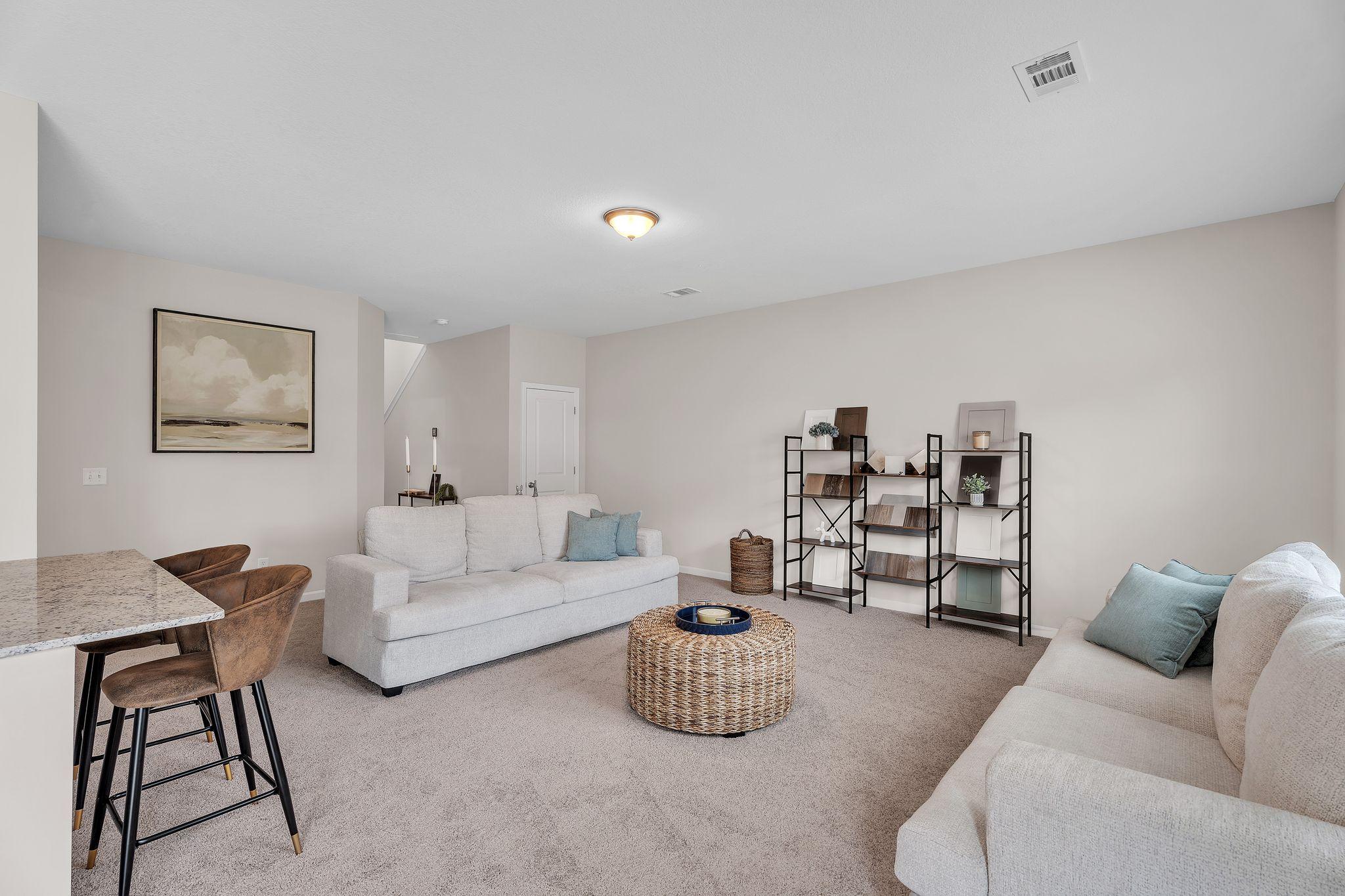 Cozy bonus room in Summer Vineyard home by Davidson Homes, Phenix City AL with white sofas, bar stools, and neutral decor