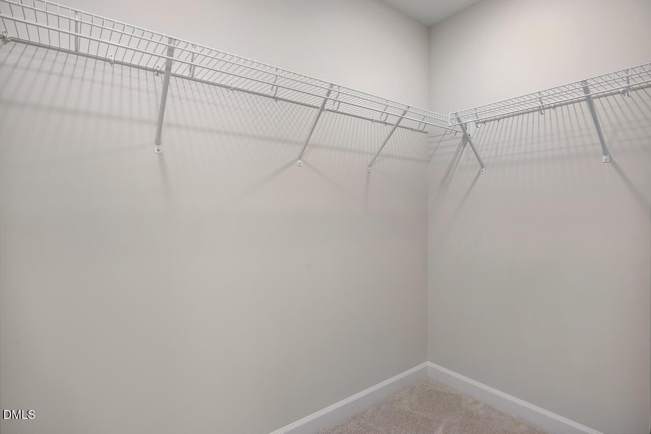 Walk-in closet with white wire shelving in The Mitchell Interior floor plan at Forestville Yard Townhomes, Knightdale, NC.