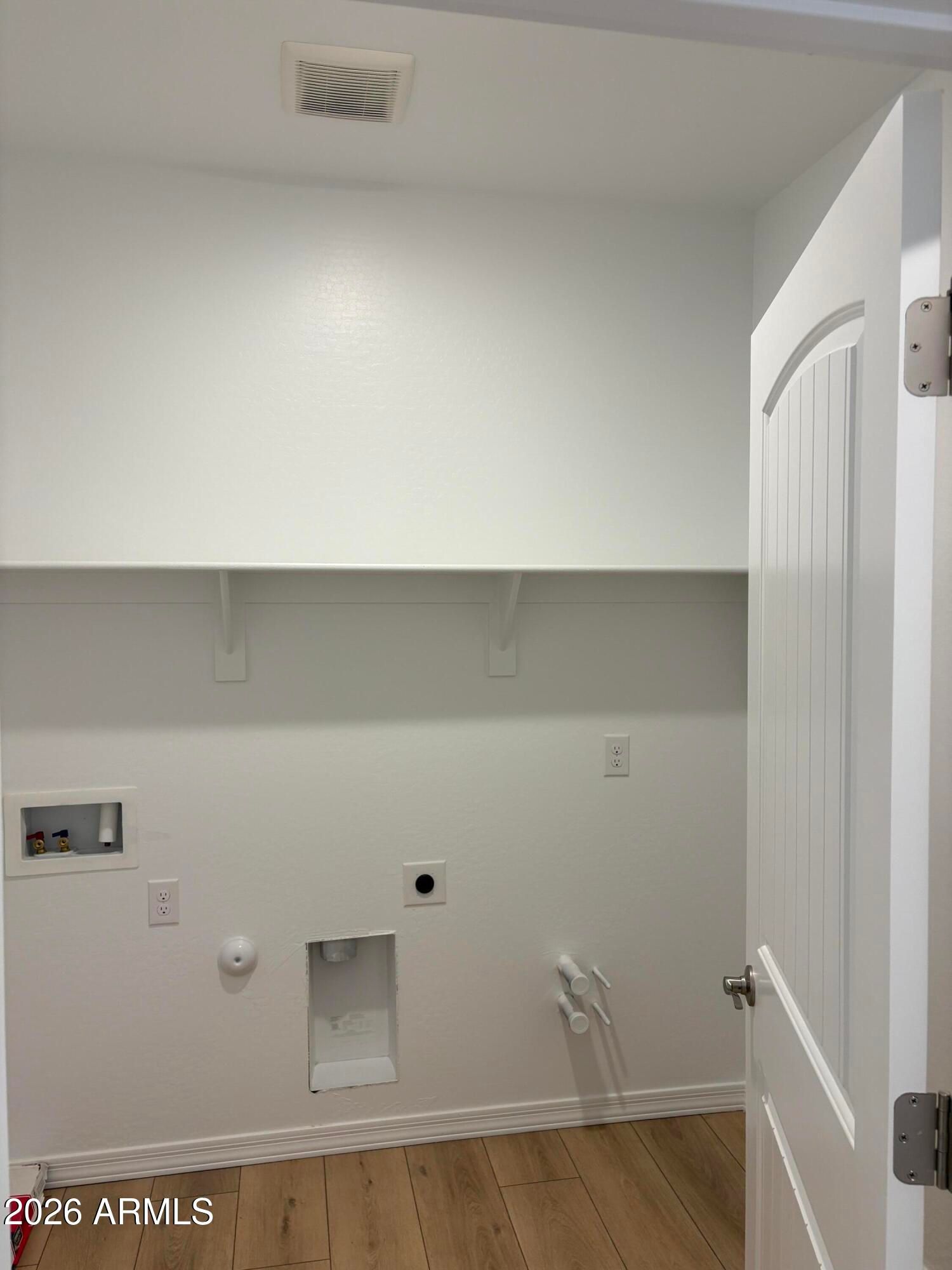 Laundry room with white shelving, washer hookups, and wood-look flooring in Davidson Homes The Evergreen B, Cottonwood, Arizona