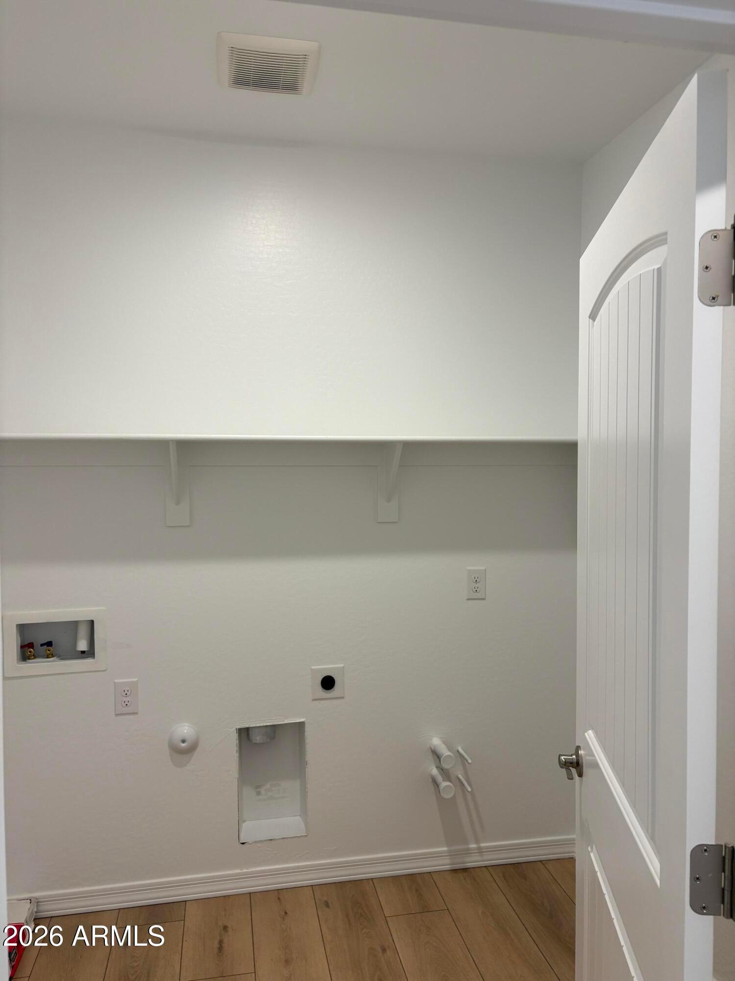 Laundry room with white shelving, washer hookups, and wood-look flooring in Davidson Homes The Evergreen B, Cottonwood, Arizona