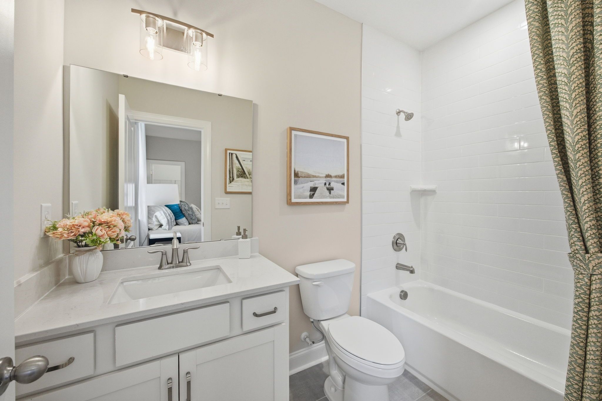 Modern bathroom with white vanity, quartz countertop, and tub-shower combo at Enclave at Belmont in Belmont, NC.