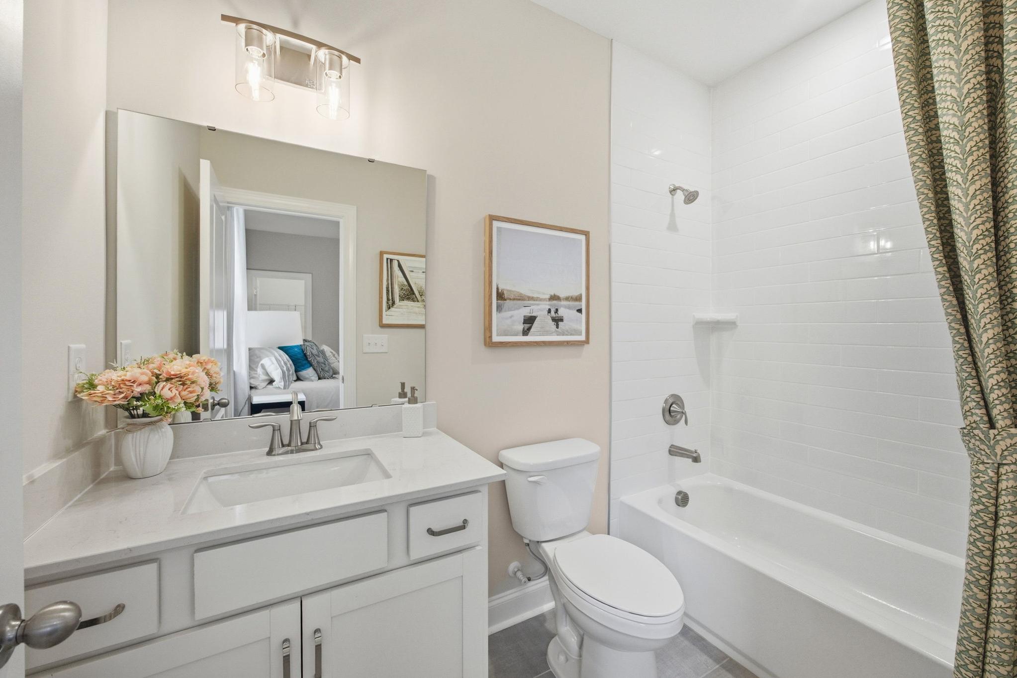 Modern bathroom with white vanity, quartz countertop, and tub-shower combo at Enclave at Belmont in Belmont, NC.
