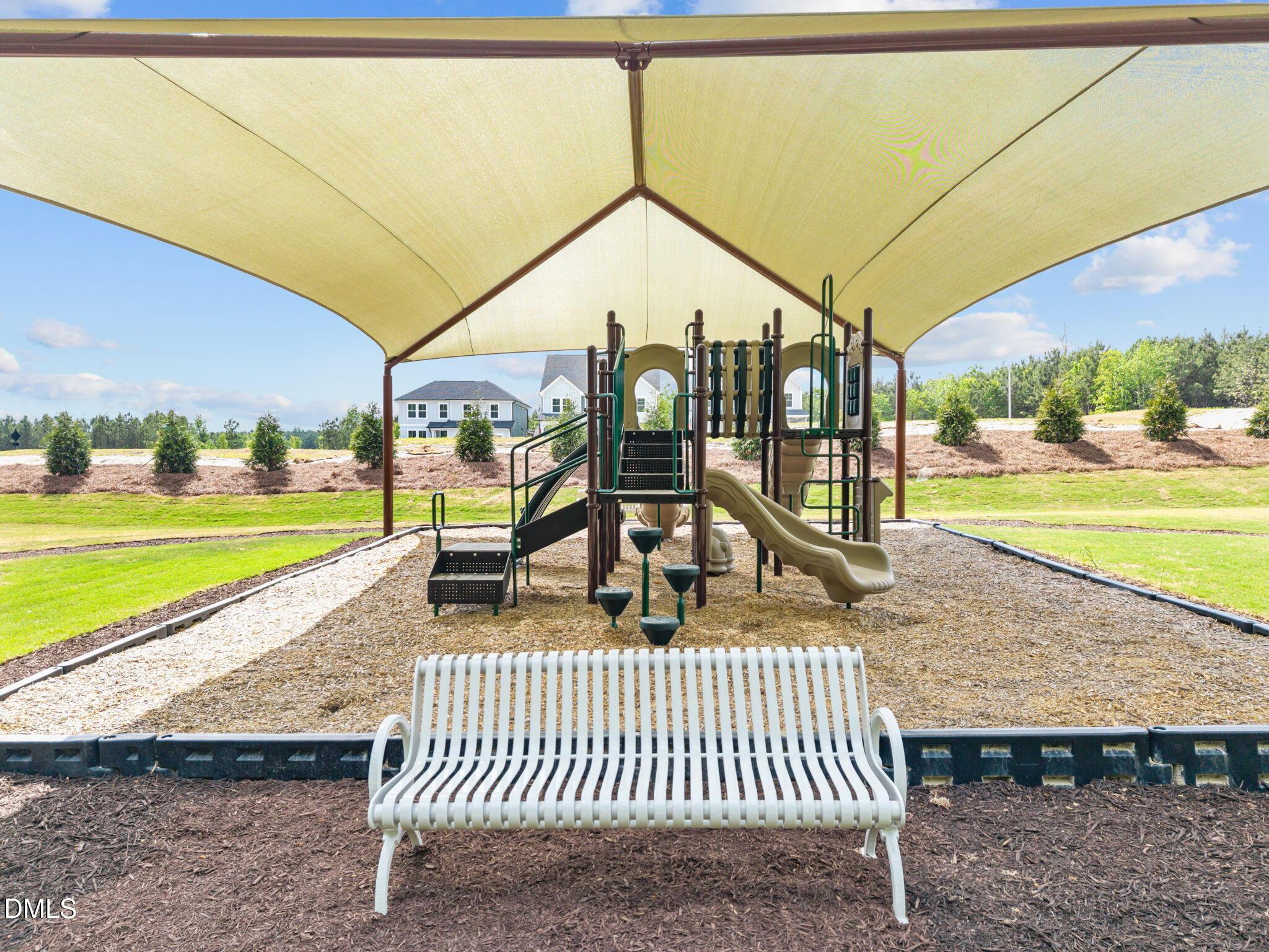 Shaded playground with slide, climbing arches, and white bench in Wendell Ridge community, Wendell, North Carolina