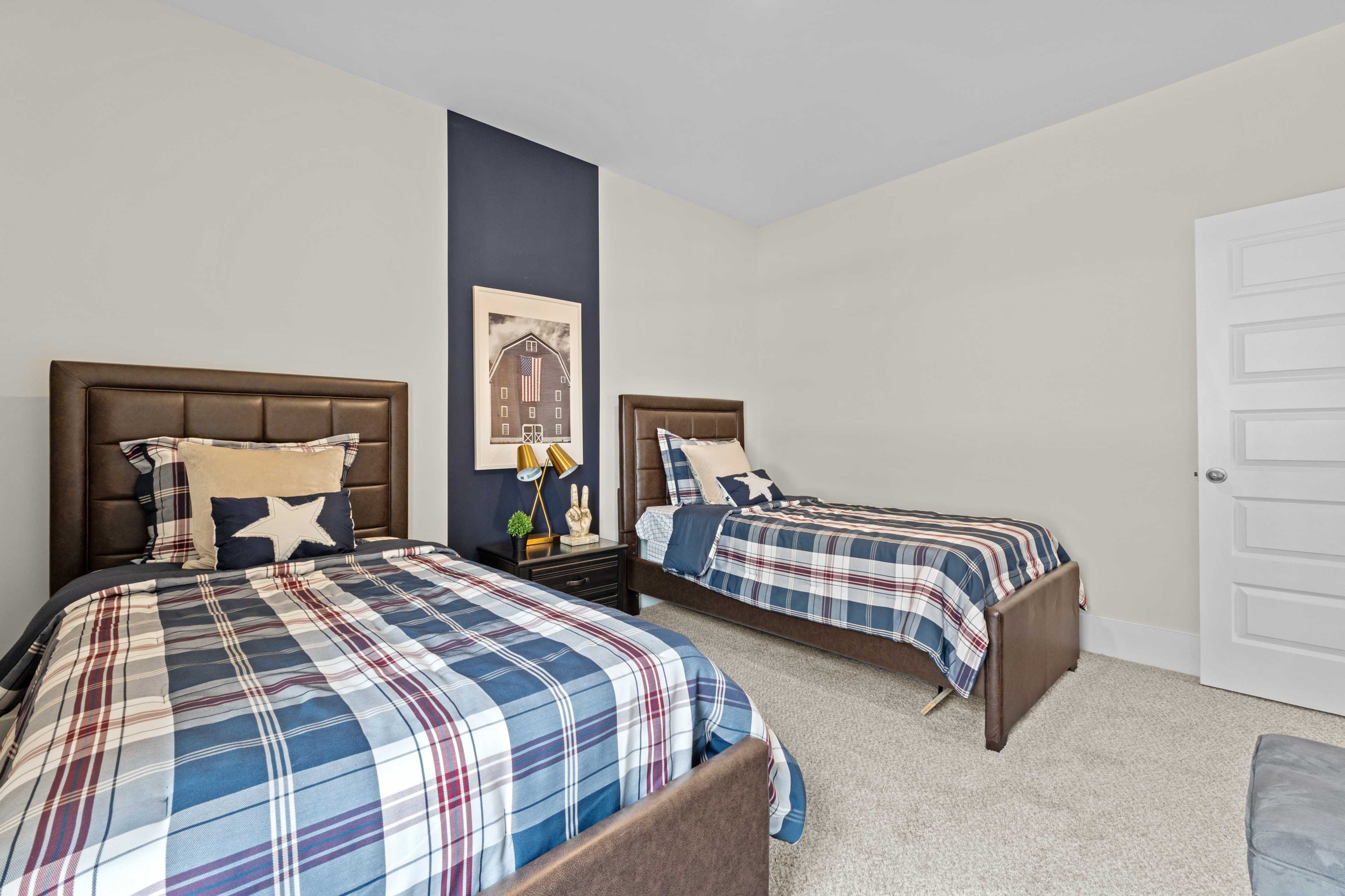 Shared boys' bedroom at Ivy Hills in Toney, Alabama with twin beds, plaid bedding, navy accent wall, and upholstered headboards
