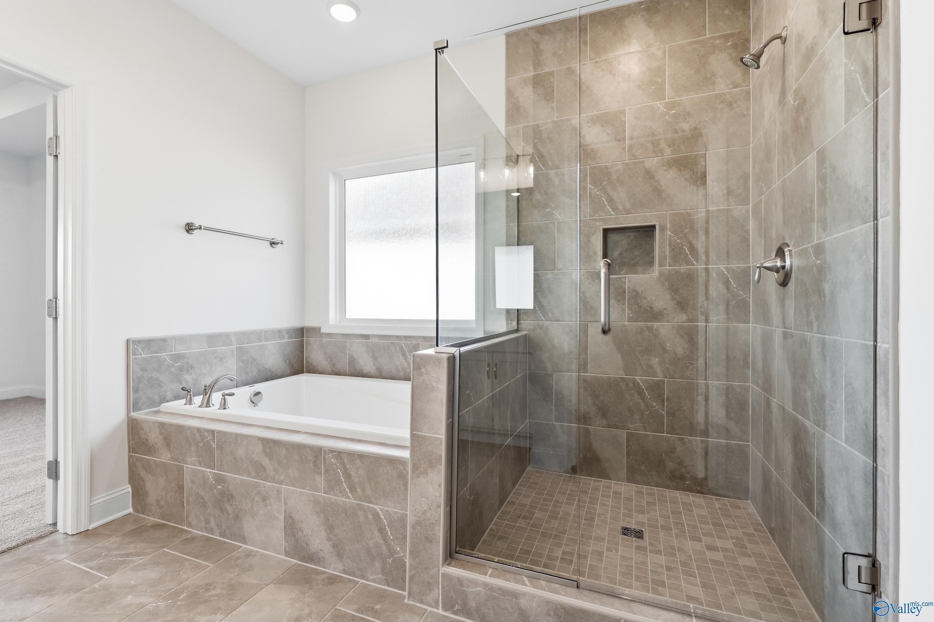 Luxurious master bathroom with frameless glass shower, soaking tub and tile surround in Davidson Homes The Montgomery C, Harvest AL