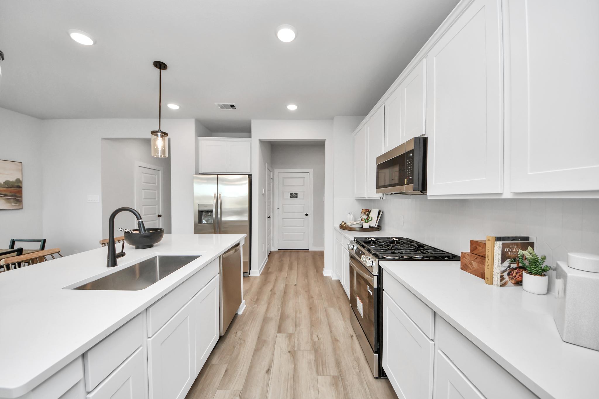 Modern kitchen at Robins Landing in Houston with white cabinetry, stainless appliances, and a large center island.