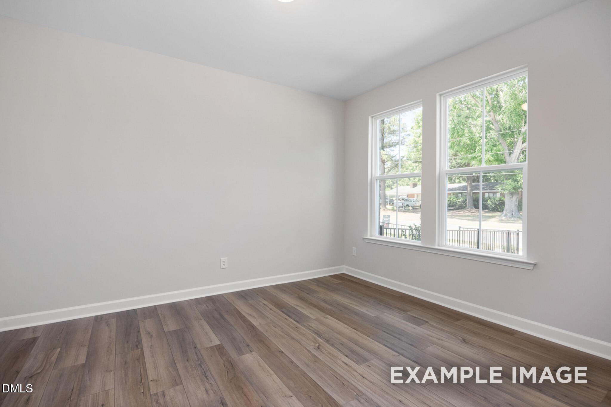 Bright bedroom with wood-style flooring in The Mitchell Interior floor plan at Camden Park, Knightdale, North Carolina.