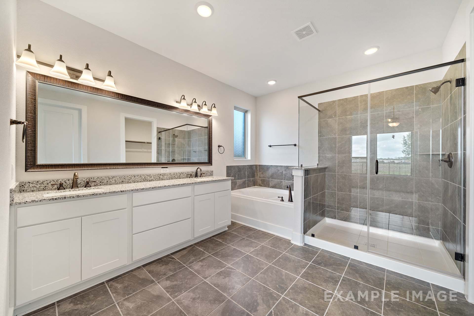 Master bathroom in The Victoria by Davidson Homes featuring dual vanity, garden tub, and glass walk-in shower, Texas City.
