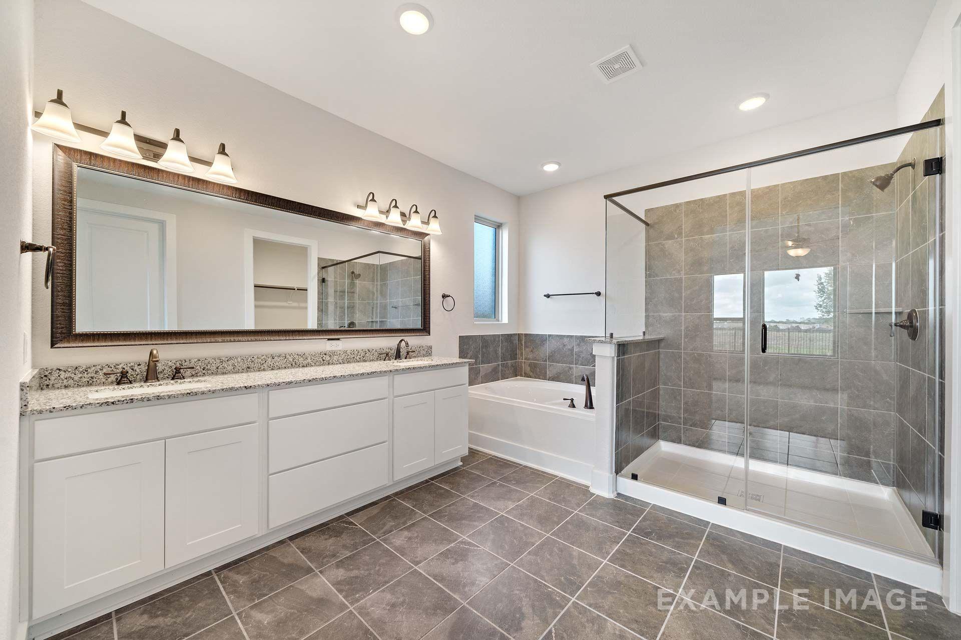 Master bathroom in The Victoria by Davidson Homes featuring dual vanity, garden tub, and glass walk-in shower, Texas City.