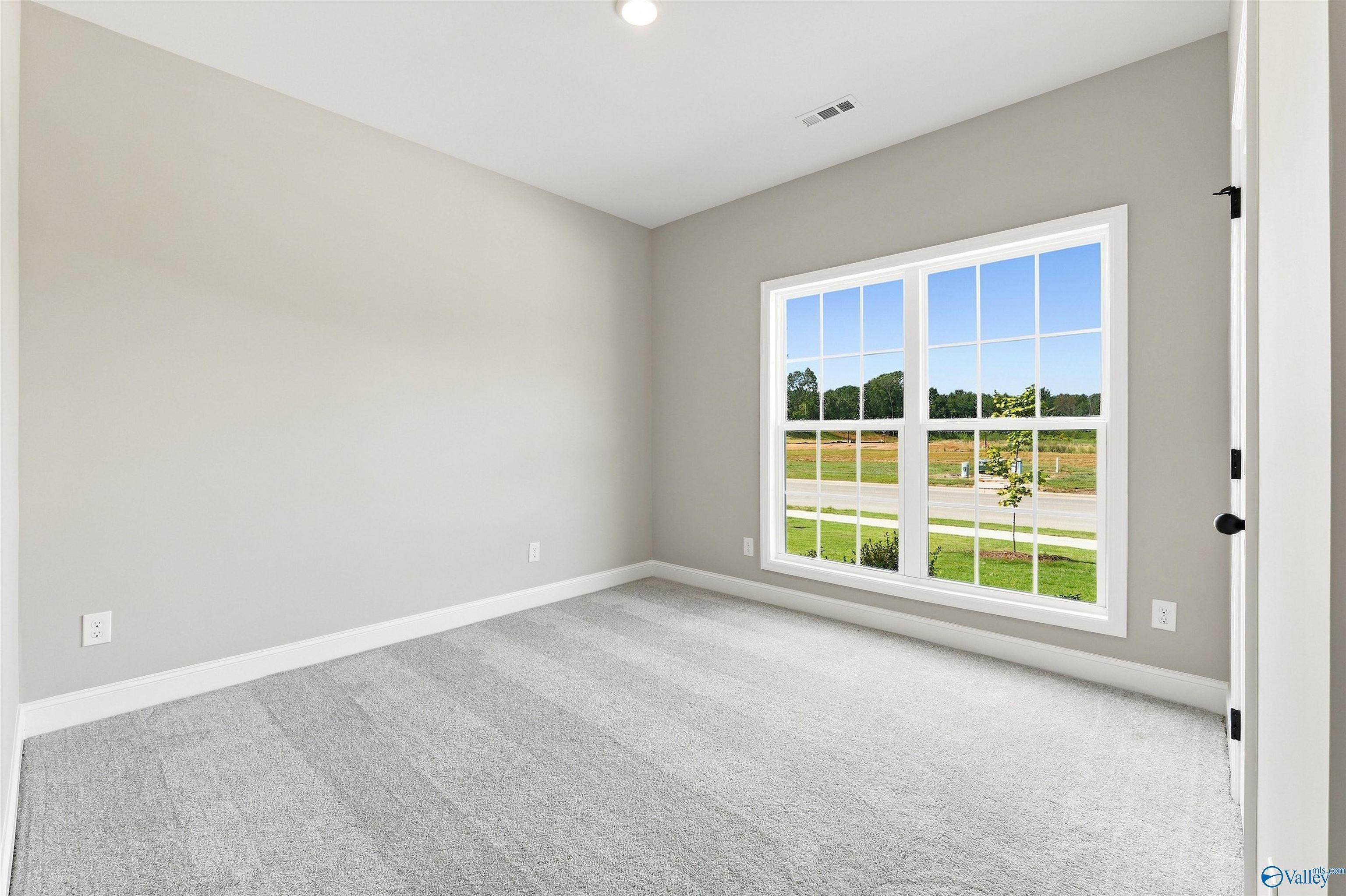 Bright carpeted bedroom with large double-hung window in Davidson Homes The Franklin C, Wood Trail, Toney, Alabama