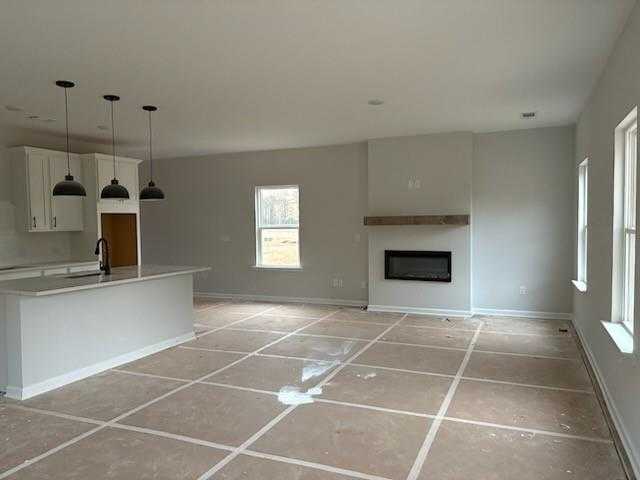 Open-concept kitchen-living room with white island, pendant lights, and linear gas fireplace in Davidson Homes The Rabun C, Winder, GA