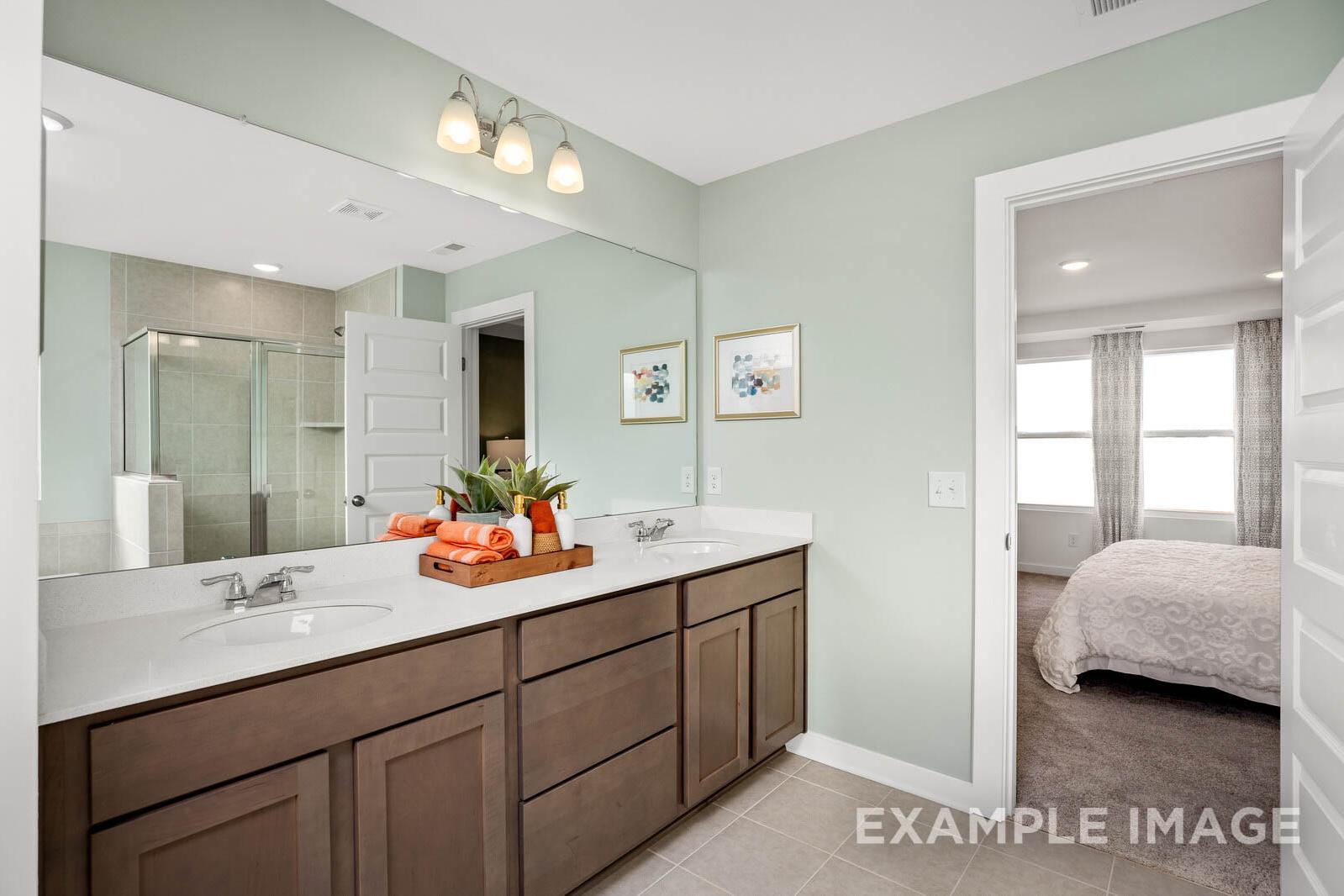 Master bathroom in The Gordon C featuring double vanity, walk-in shower, green walls, and bedroom view