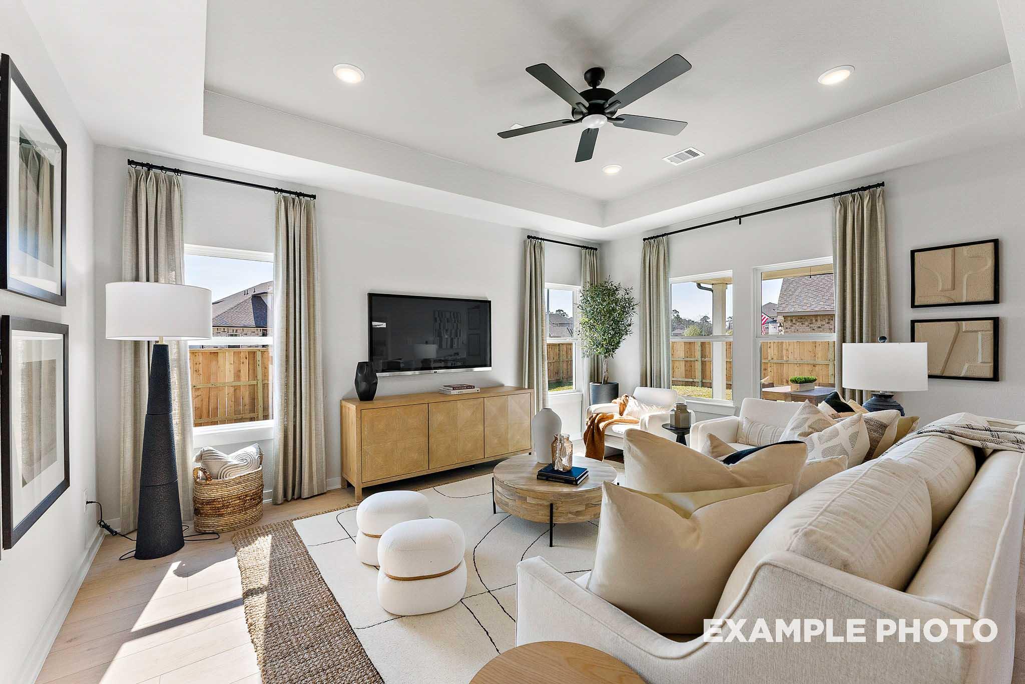 Bright, open-concept living room with tray ceiling in The Everett E floor plan at Sundance Cove, Crosby, Texas.