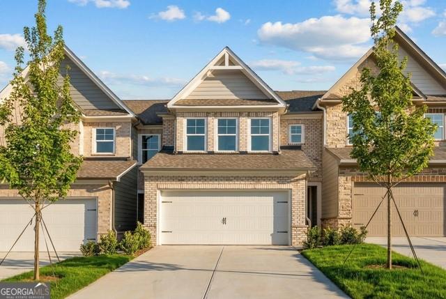 Exterior of 2-story brick home with 2-car garage and landscaped yard at Lake Shore by Davidson Homes in Winder, Georgia