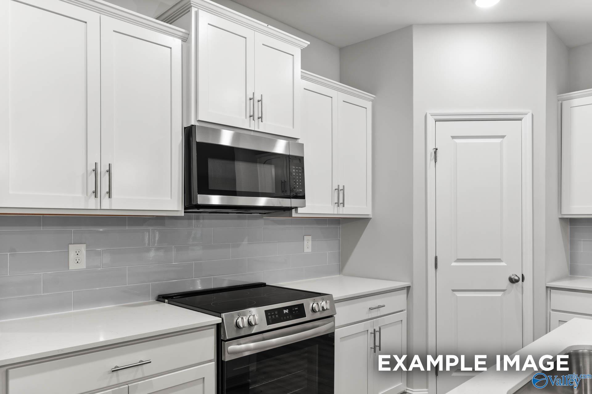 Modern kitchen with white shaker cabinets, stainless steel appliances, gray subway tile backsplash in Davidson Homes The Daphne, Meridianville, AL