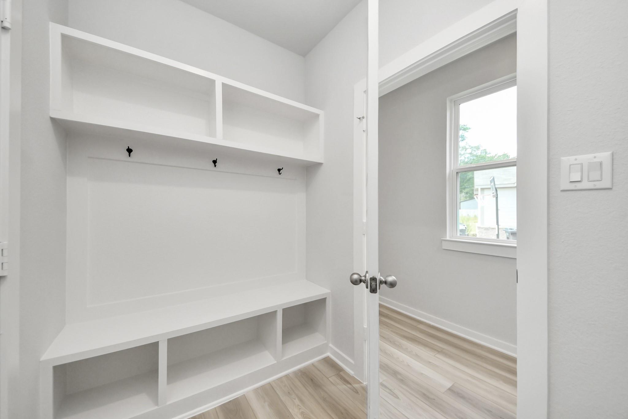White built-in mudroom bench with cubbies, hooks, and shelves in Davidson Homes The Sabine F plan, Liberty Estates, Cleveland, TX