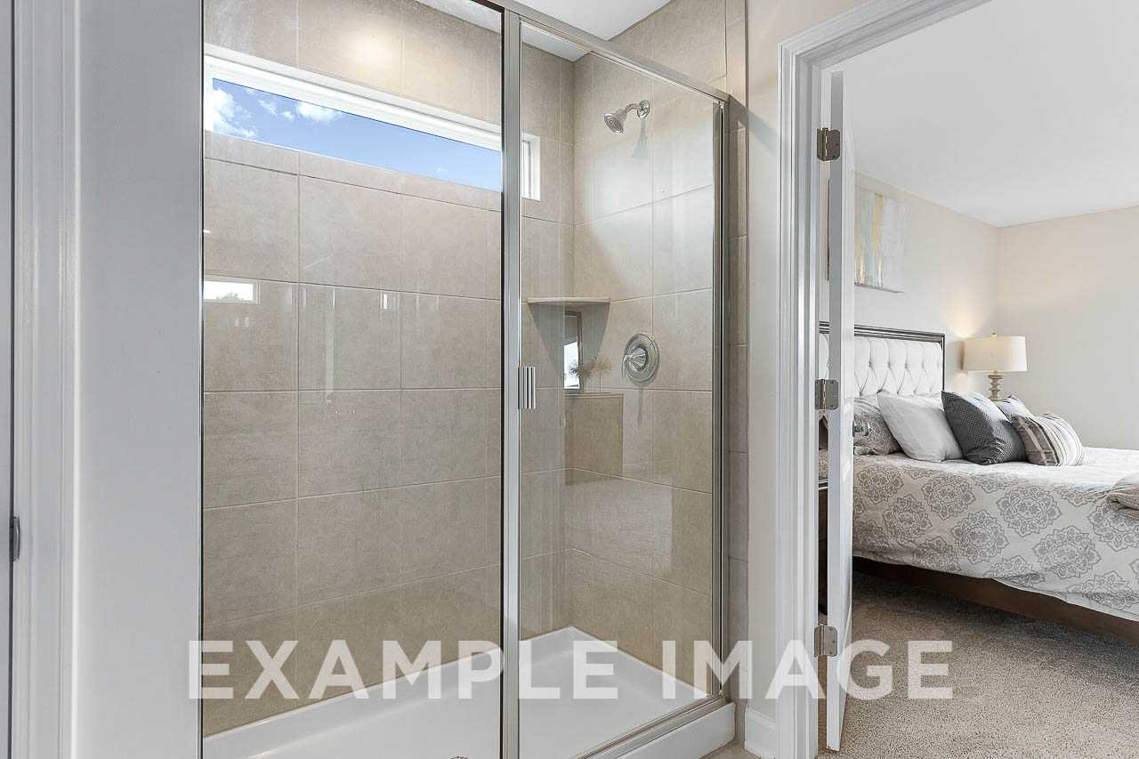 Modern master bathroom in The Willow C featuring glass walk-in shower with tile surround and adjacent bedroom suite