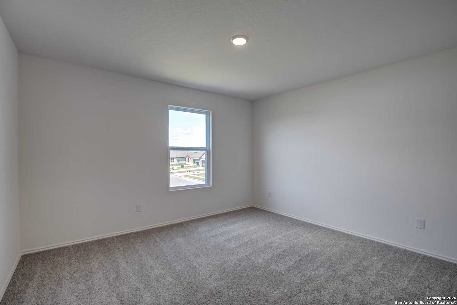 Bright secondary bedroom with white walls, gray carpet, and window view in Davidson Homes The Douglas B, Seguin, Texas