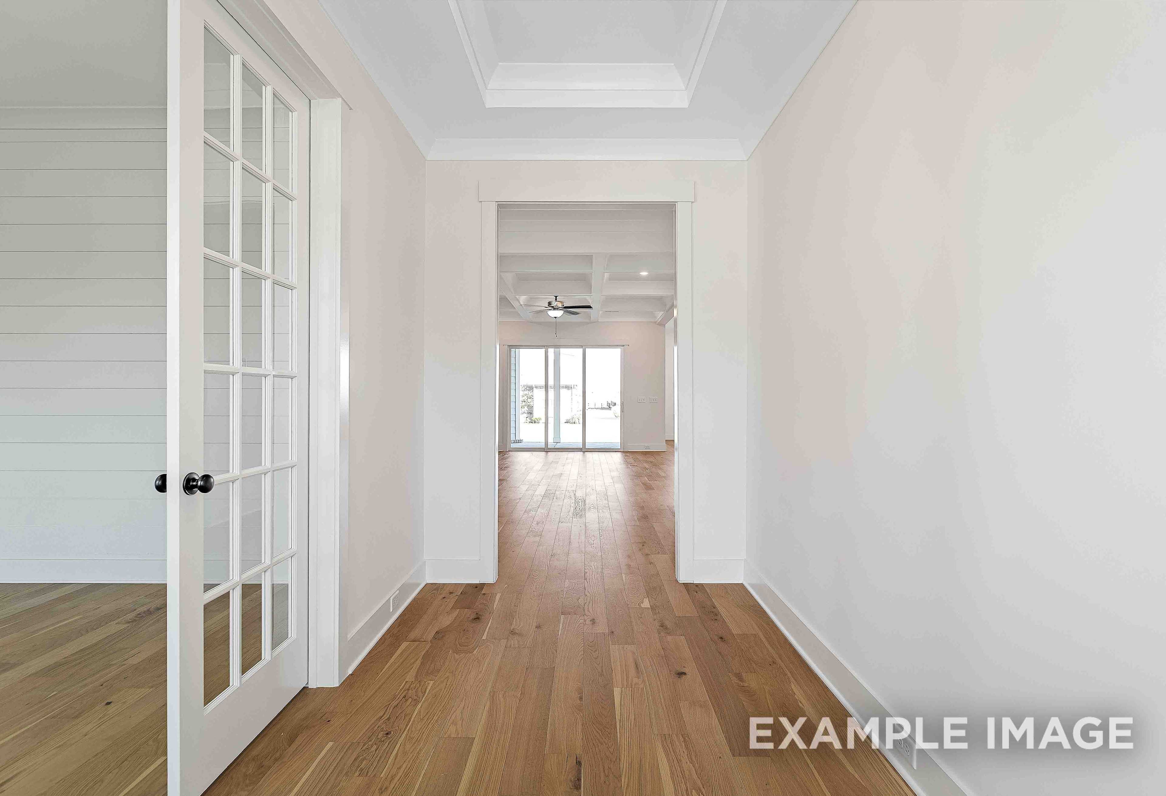 Spacious hallway in The Albany A showcasing hardwood floors, white walls, French doors, and open archway in Murfreesboro TN