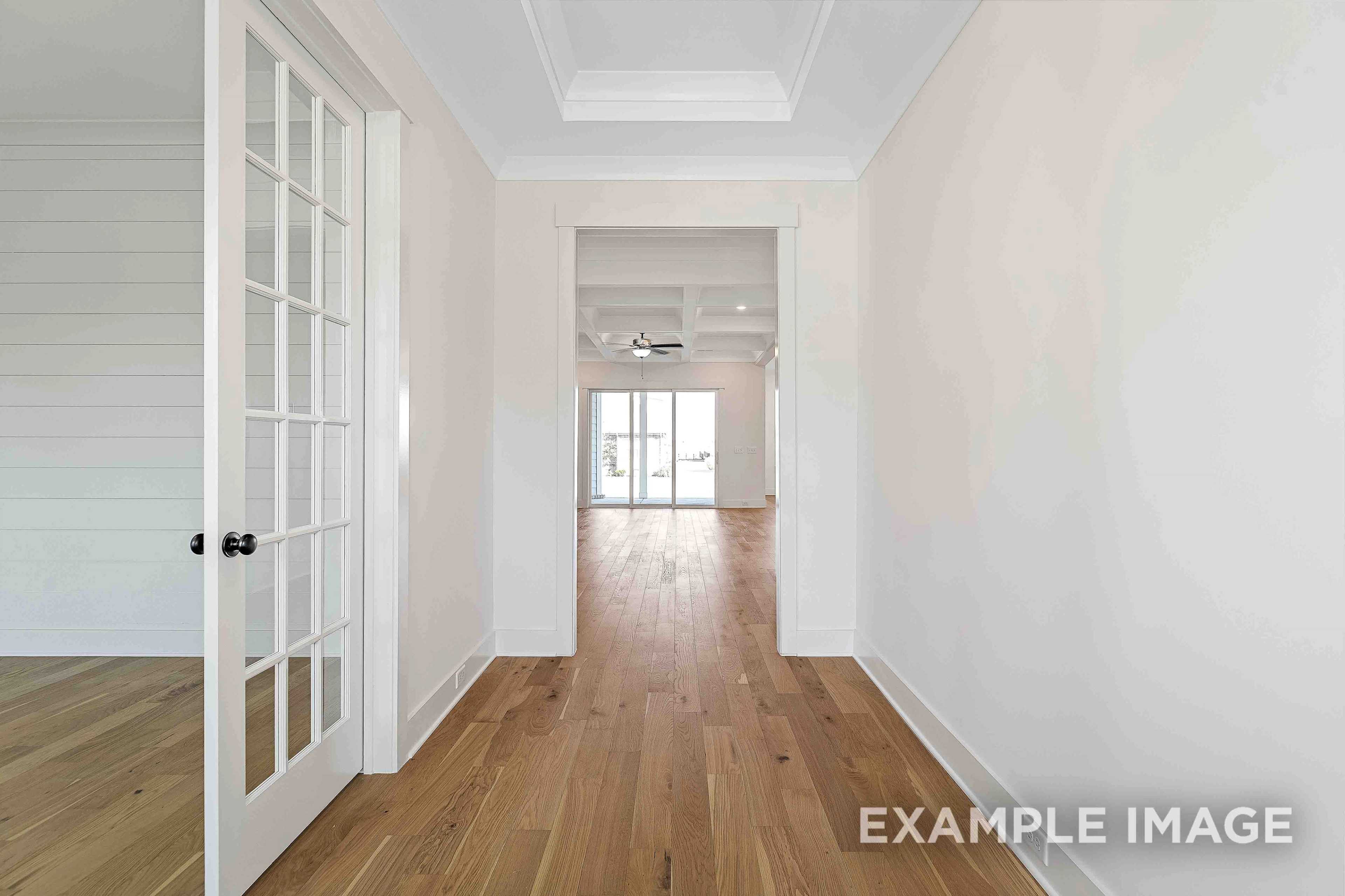 Spacious hallway in The Albany A showcasing hardwood floors, white walls, French doors, and open archway in Murfreesboro TN