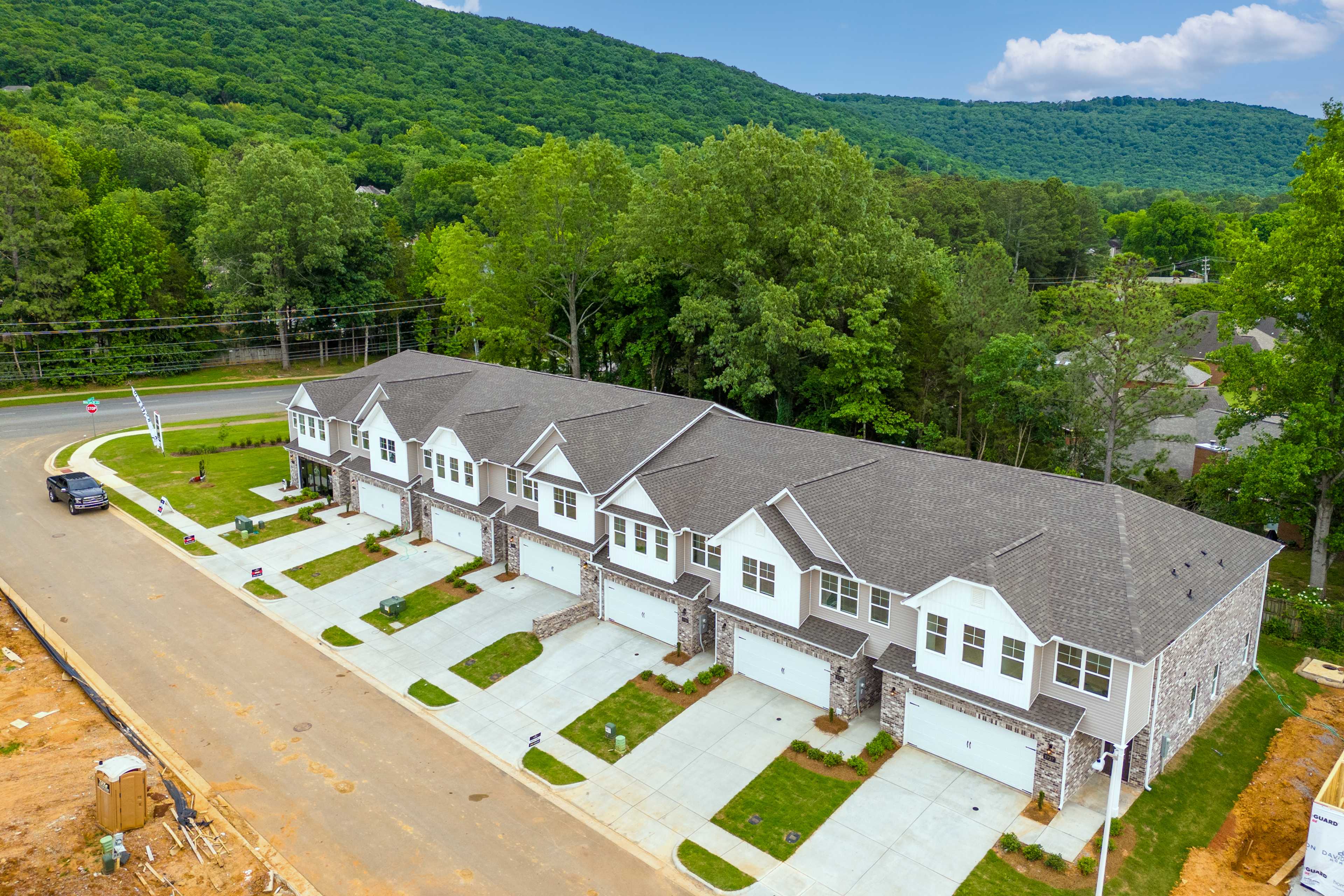Aerial view of modern townhomes at The Pavilion in Huntsville Alabama with garages driveways and lush green hillside backdrop
