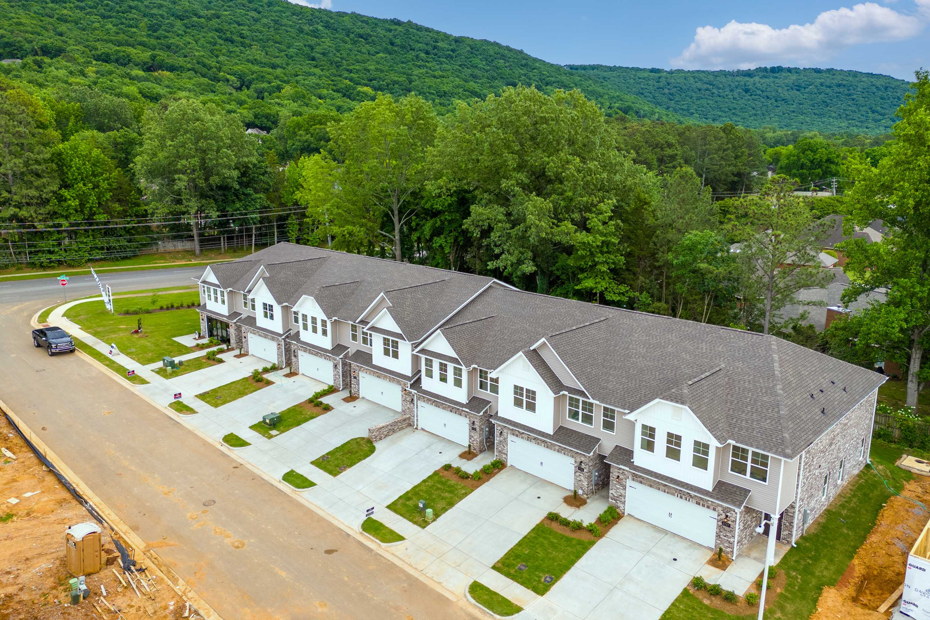 Aerial view of modern townhomes at The Pavilion in Huntsville Alabama with garages driveways and lush green hillside backdrop