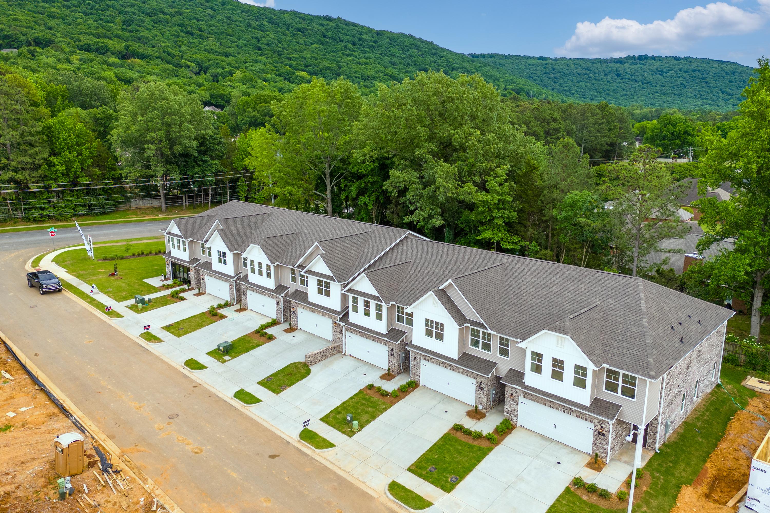 Aerial view of modern townhomes at The Pavilion in Huntsville Alabama with garages driveways and lush green hillside backdrop