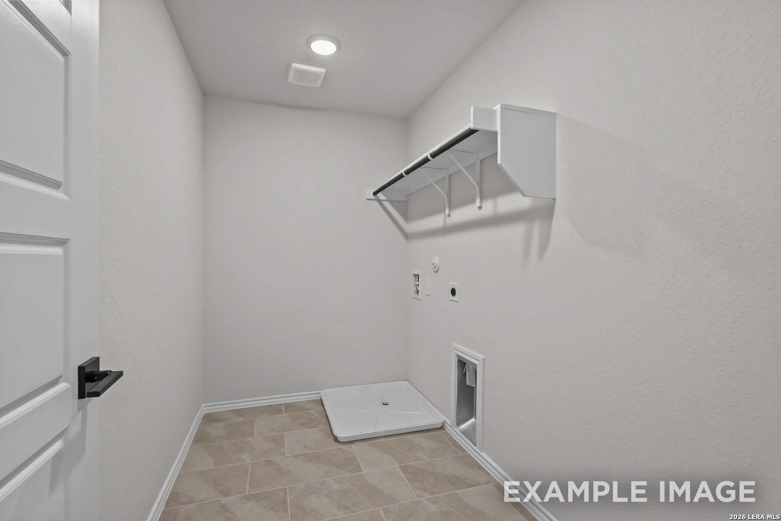 Dedicated laundry room with tile flooring and storage shelving in The Florence D floor plan by Davidson Homes.