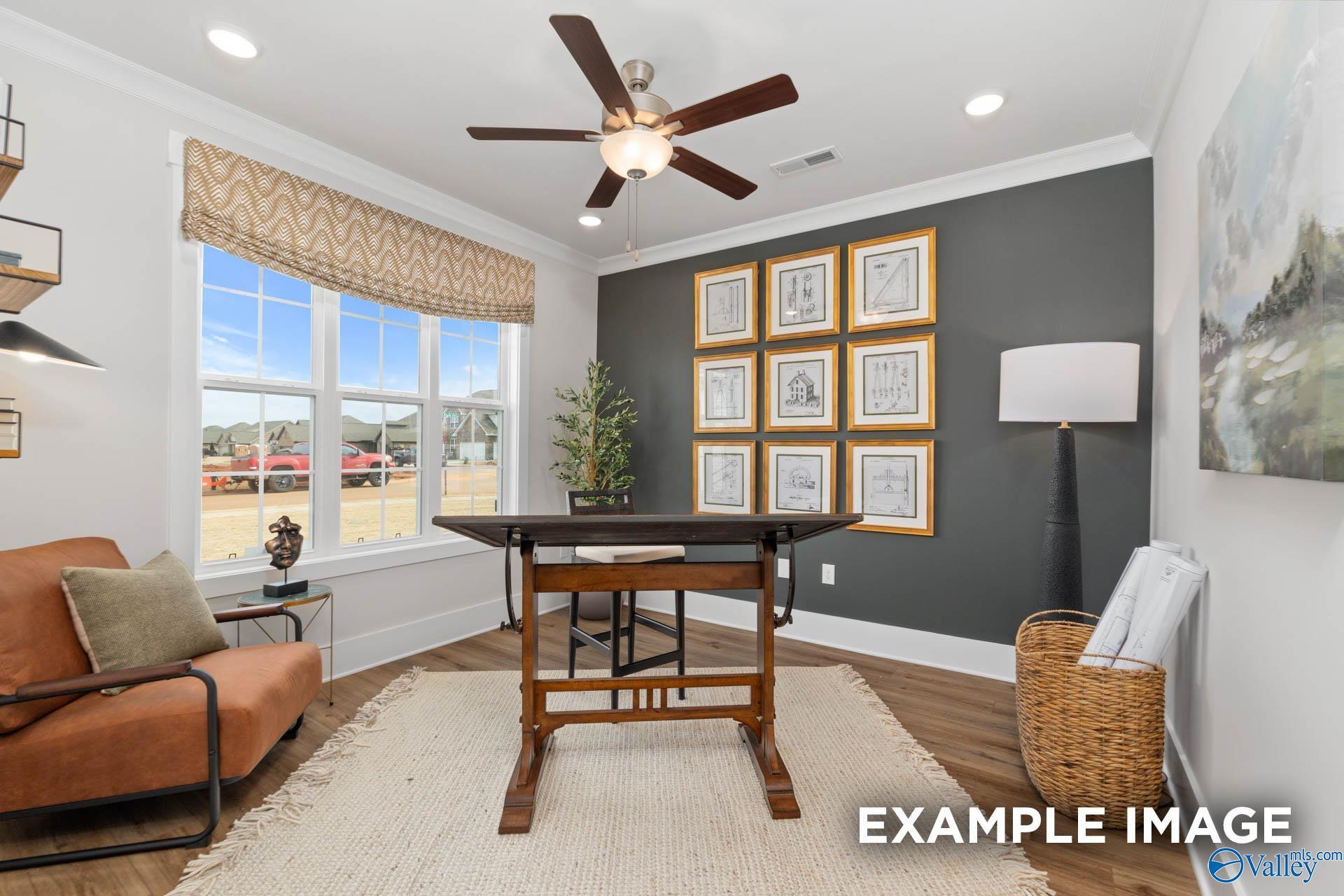 Cozy home office with wooden desk, orange armchair, gray accent wall, and large windows in Davidson Homes The Finleigh, Decatur, AL
