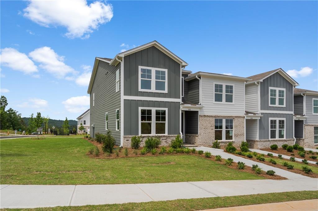 Two-story gray townhome with brick accents, white trim, and landscaped yard in Stegall Village, Emerson, Georgia by Davidson Homes