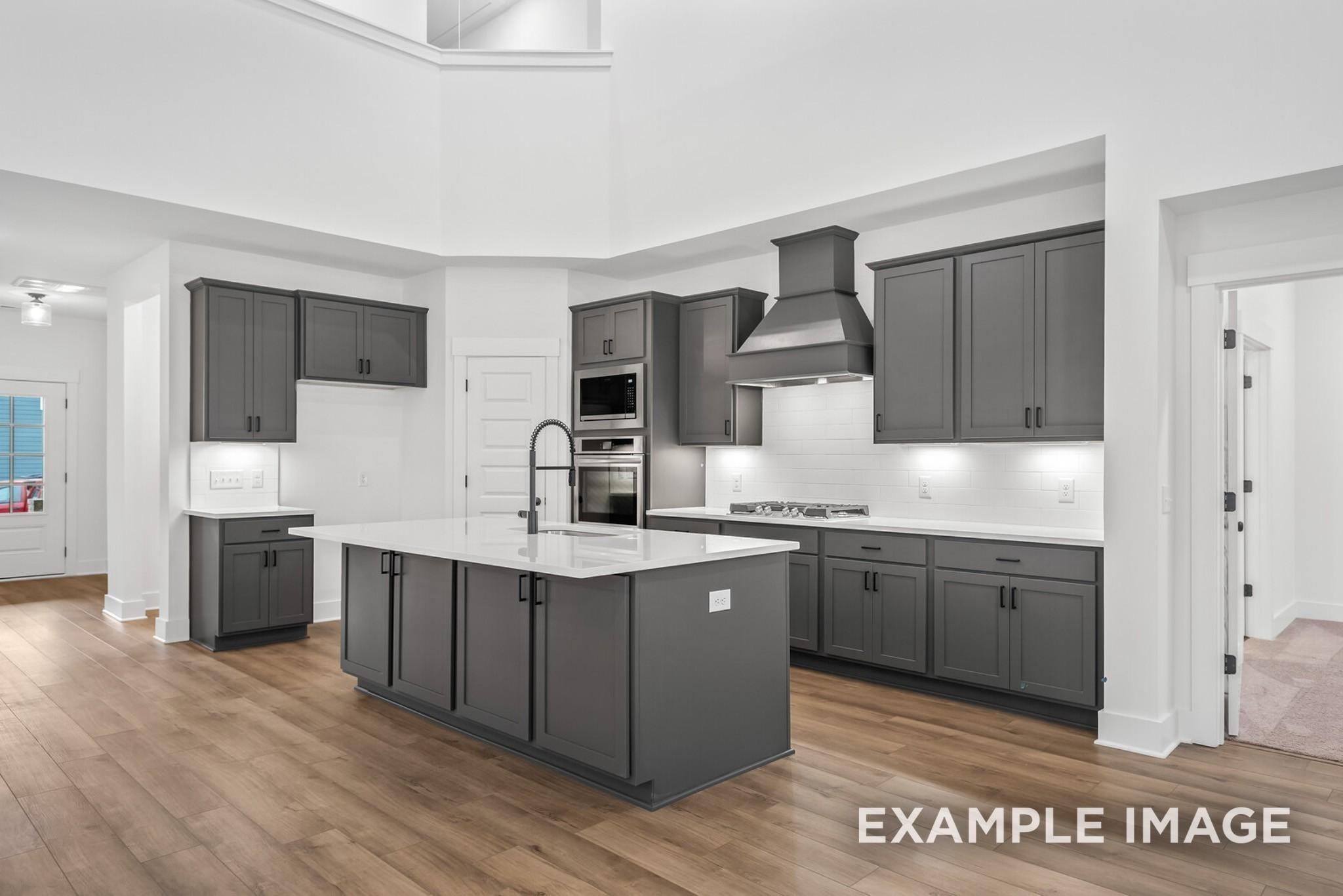 Modern gray shaker kitchen with quartz island, stainless double oven, and high ceilings in Davidson Homes Ridgeport C, Gallatin, TN