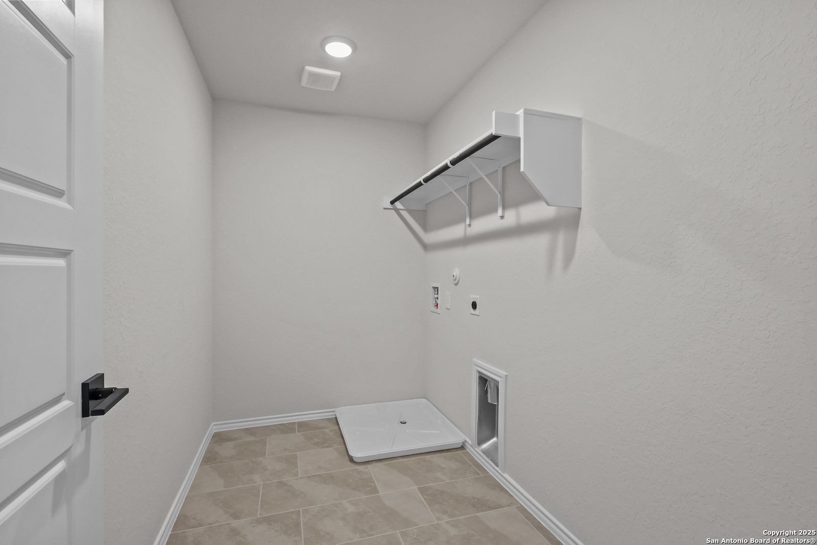 Bright laundry room with white built-in shelves, washer-dryer hookups, and pet door in Davidson Homes The Florence C, San Antonio