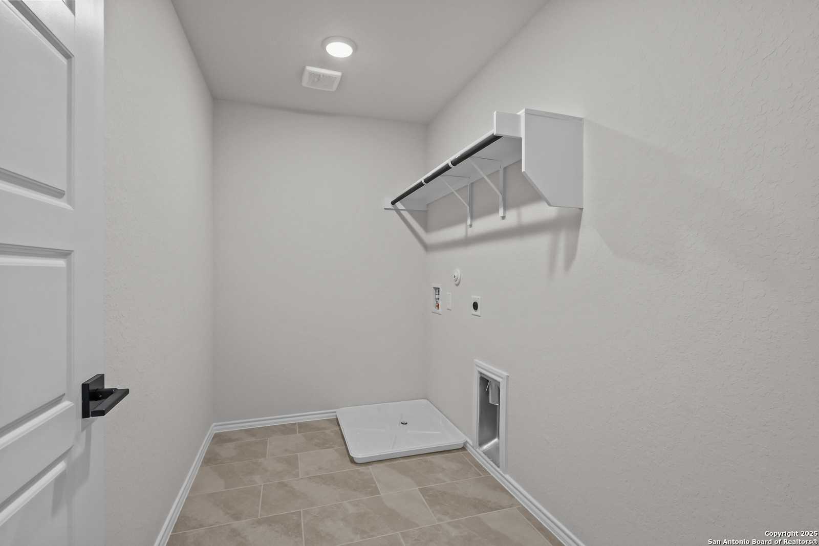 Bright laundry room with white built-in shelves, washer-dryer hookups, and pet door in Davidson Homes The Florence C, San Antonio